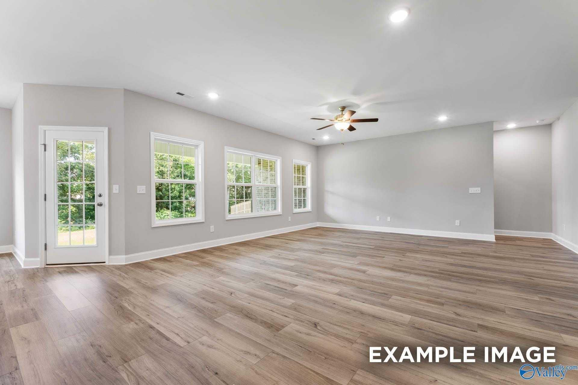 Spacious open living area with hardwood floors, ceiling fan, and large windows in Davidson Homes The Rockford D, Hazel Green, AL