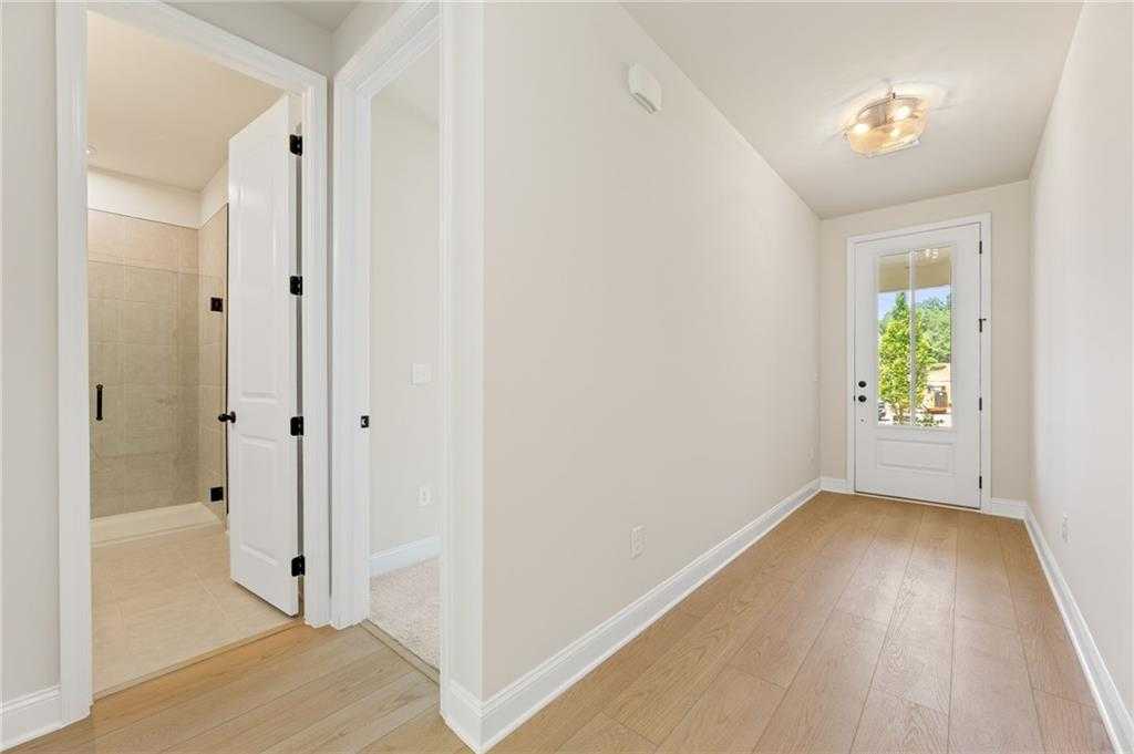 Bright hallway with oak floors, open bathroom door, and glass-paneled exterior entry in 5-bedroom Davidson Homes The Hickory E, Buford, GA