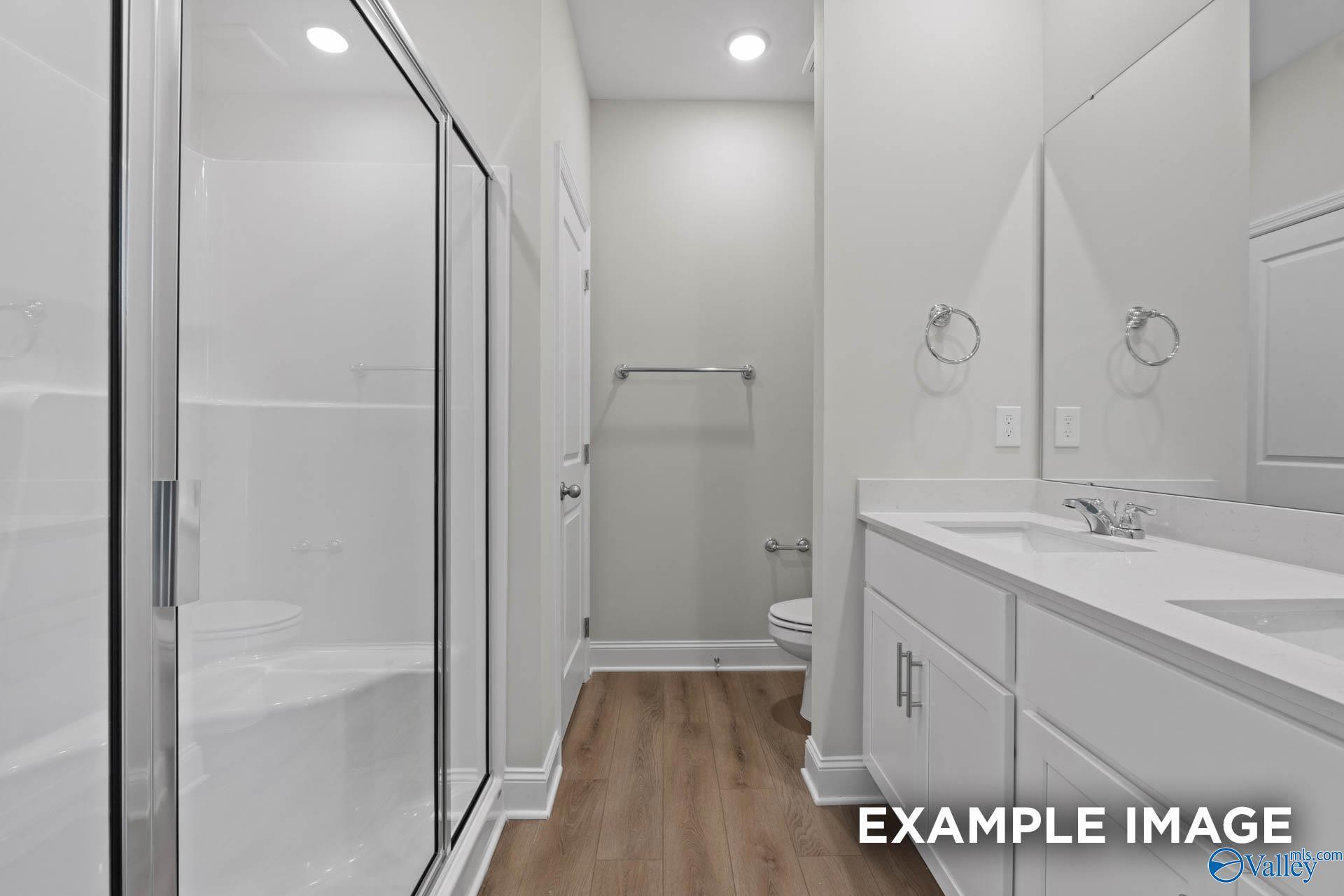 Modern bathroom with glass shower enclosure, double vanity sinks, and neutral tones in Davidson Homes The Butler, Huntsville AL