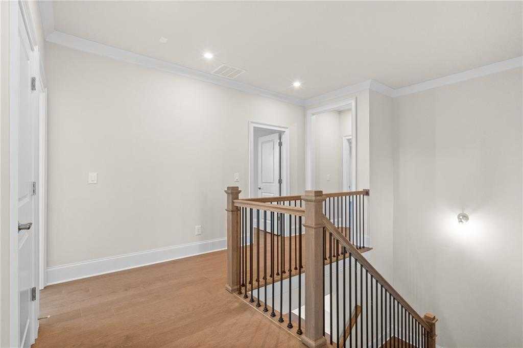 Elegant oak staircase with black balusters leading to beige upstairs hallway in Davidson Homes The Arlington A, East Cobb, Georgia