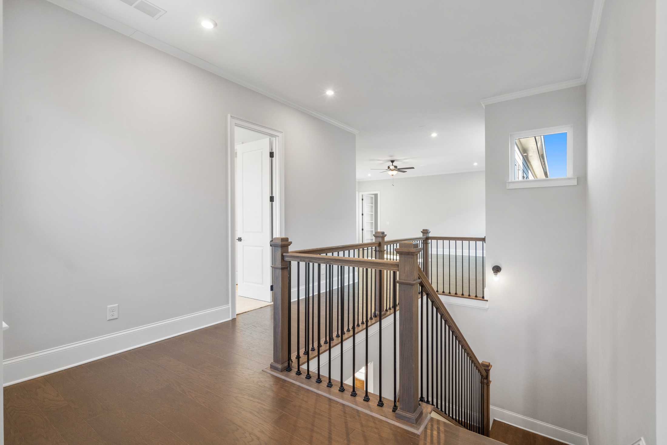 Upstairs hallway in The Seaside home design with wooden staircase, hardwood floors, and white walls, Davidson Homes Woodstock GA