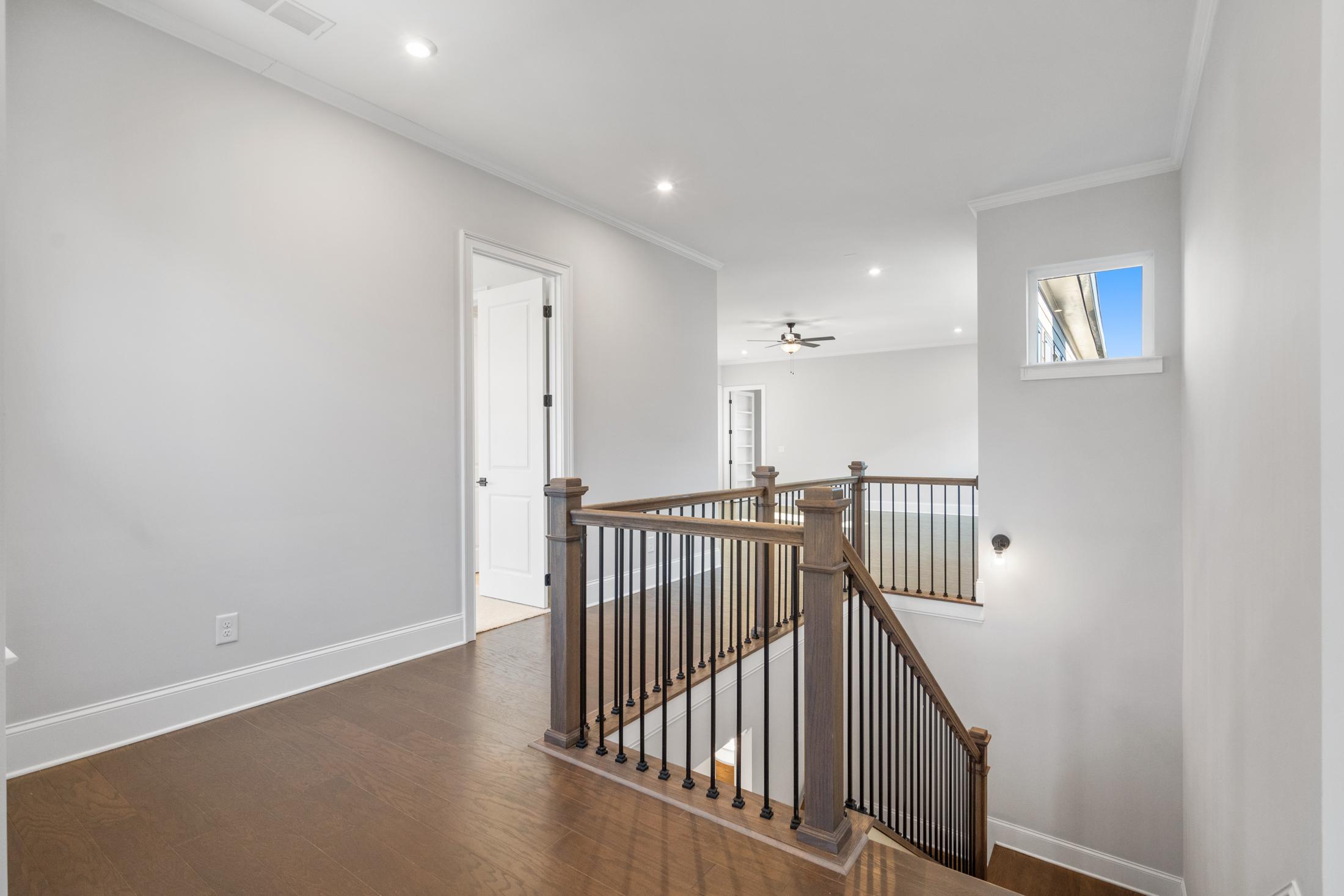 Upstairs hallway in The Seaside home design with wooden staircase, hardwood floors, and white walls, Davidson Homes Woodstock GA