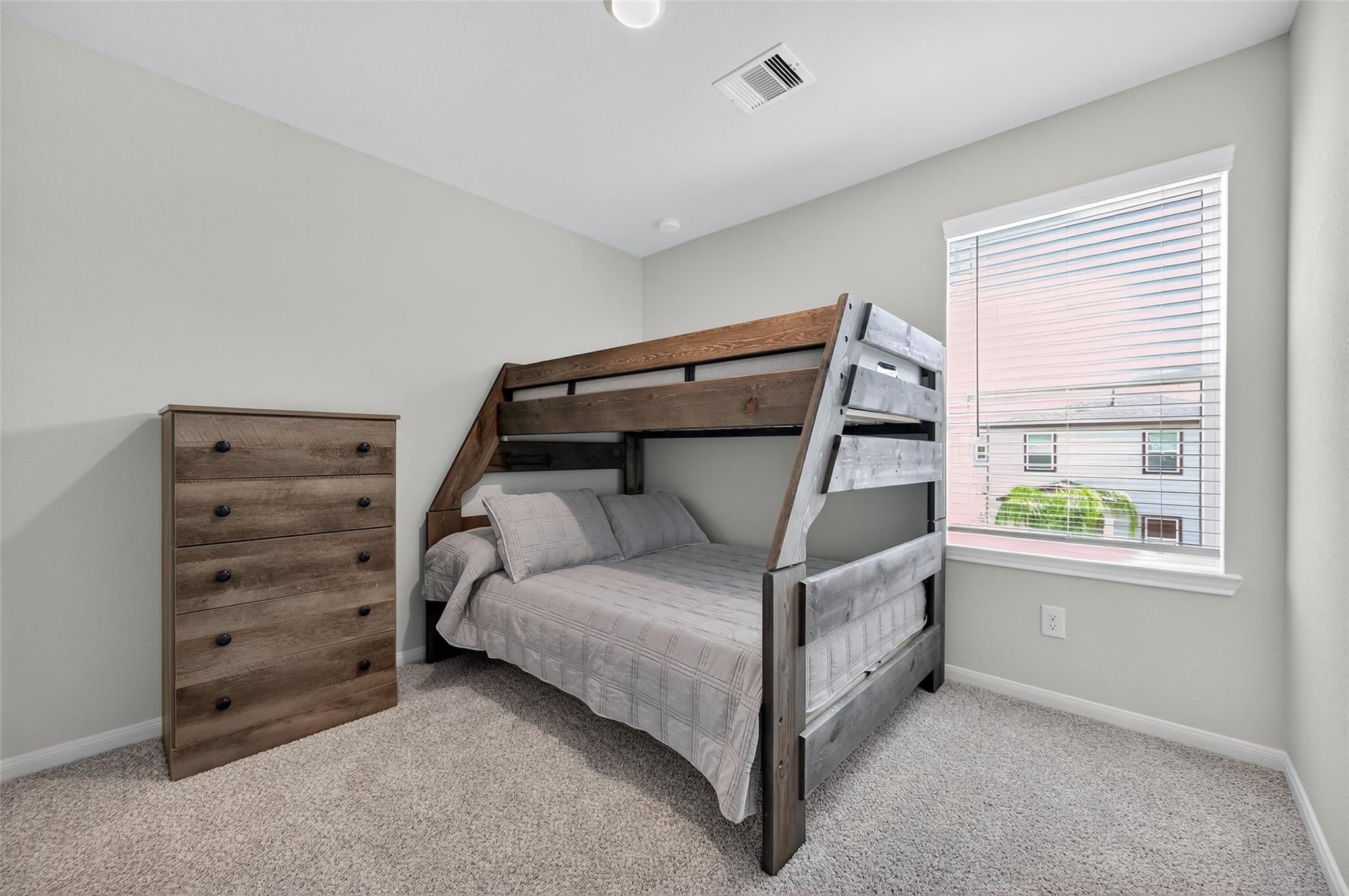 Cozy bunk bed bedroom with wooden loft bed, gray bedding and matching dresser in Davidson Homes The Brazos E, Magnolia, Texas