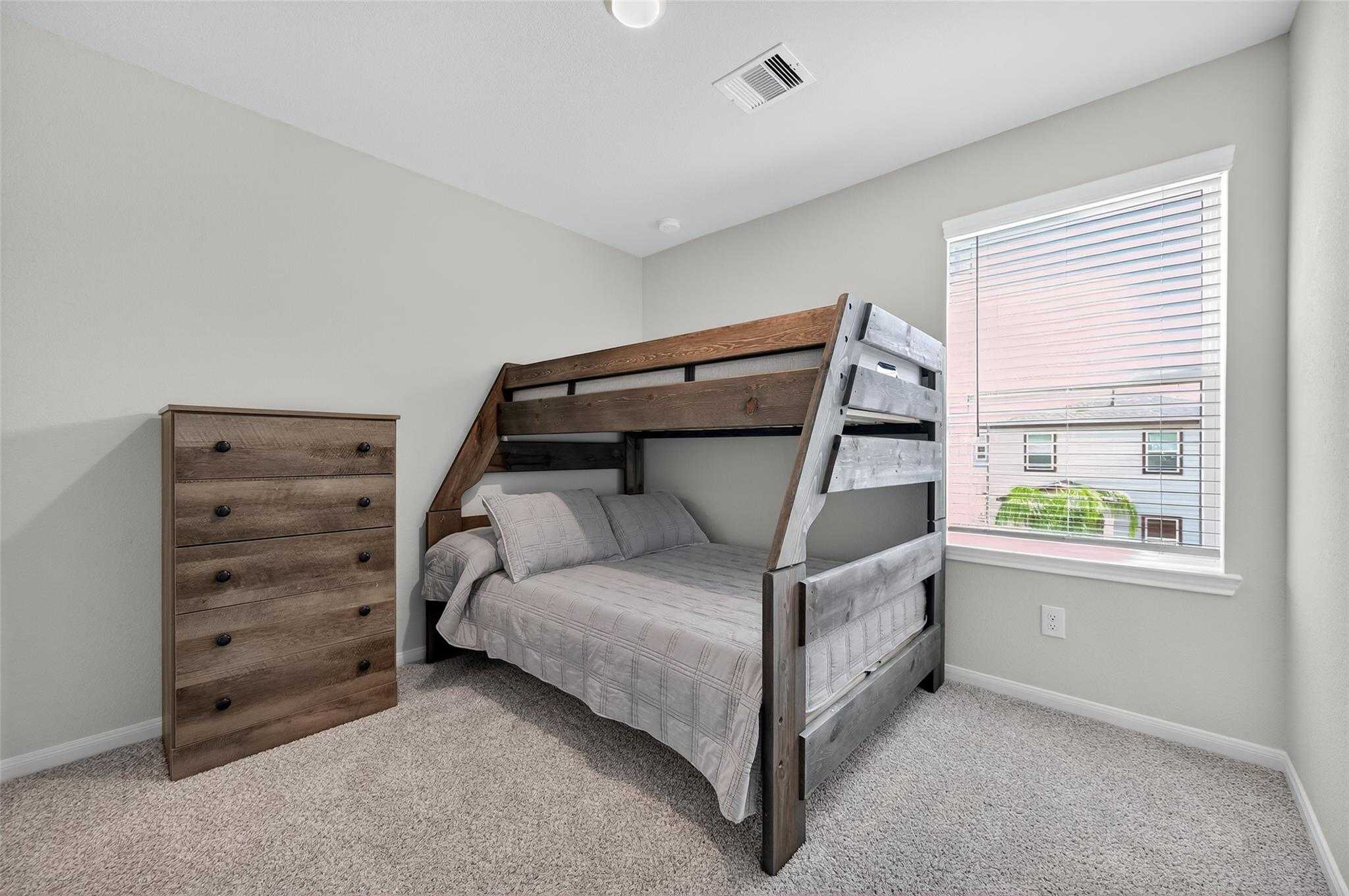 Cozy bunk bed bedroom with wooden loft bed, gray bedding and matching dresser in Davidson Homes The Brazos E, Magnolia, Texas