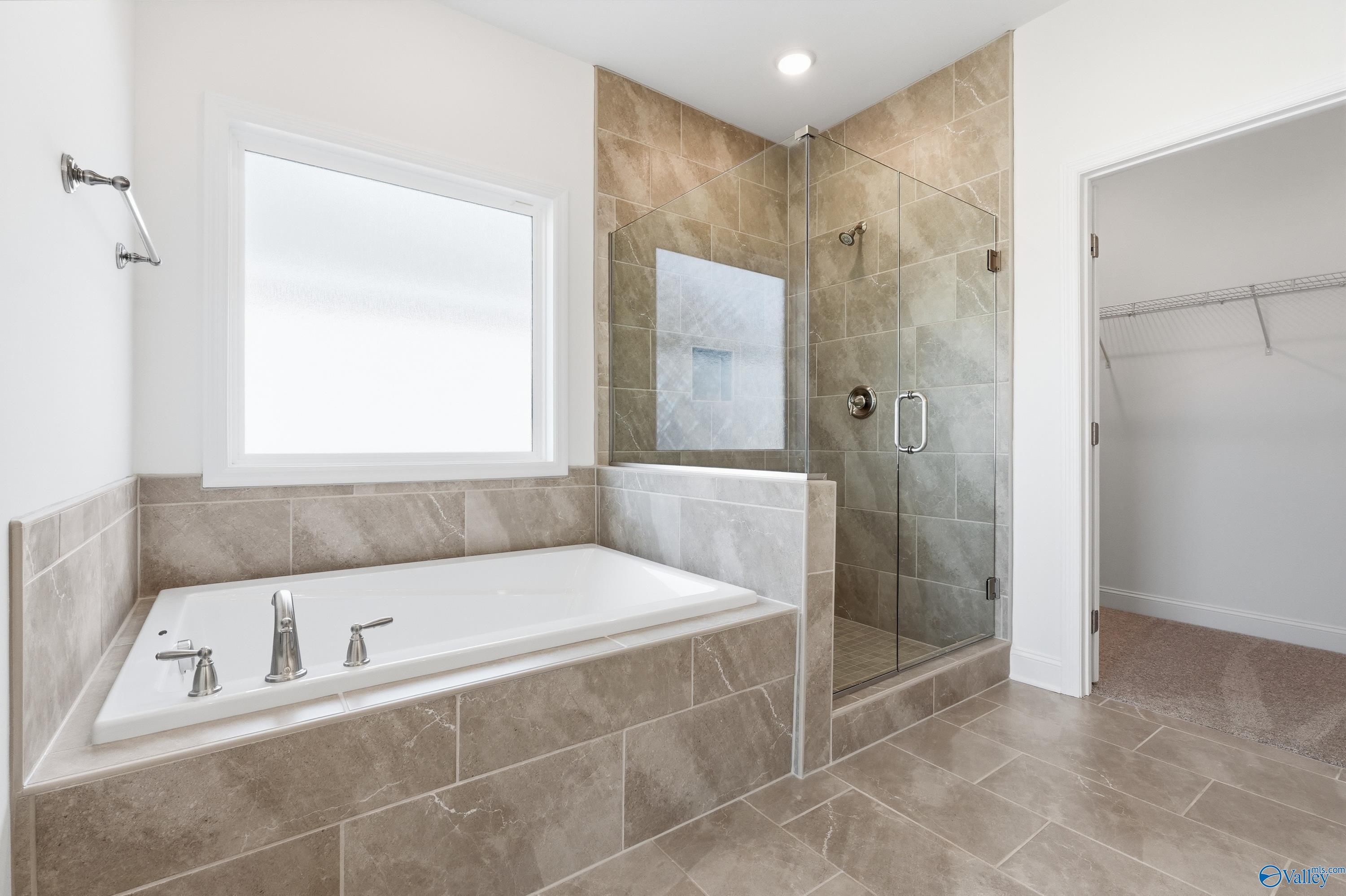 Luxurious master bathroom featuring freestanding tub, glass shower, and tiled accents in Davidson Homes The Montgomery C, Harvest, Alabama