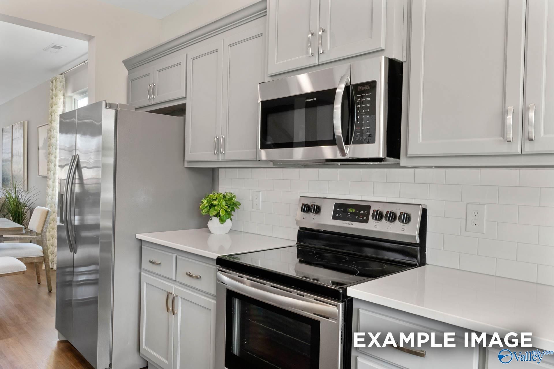 Modern kitchen with white shaker cabinets, stainless steel microwave, oven, and fridge in Davidson Homes The Stella, Madison, Alabama