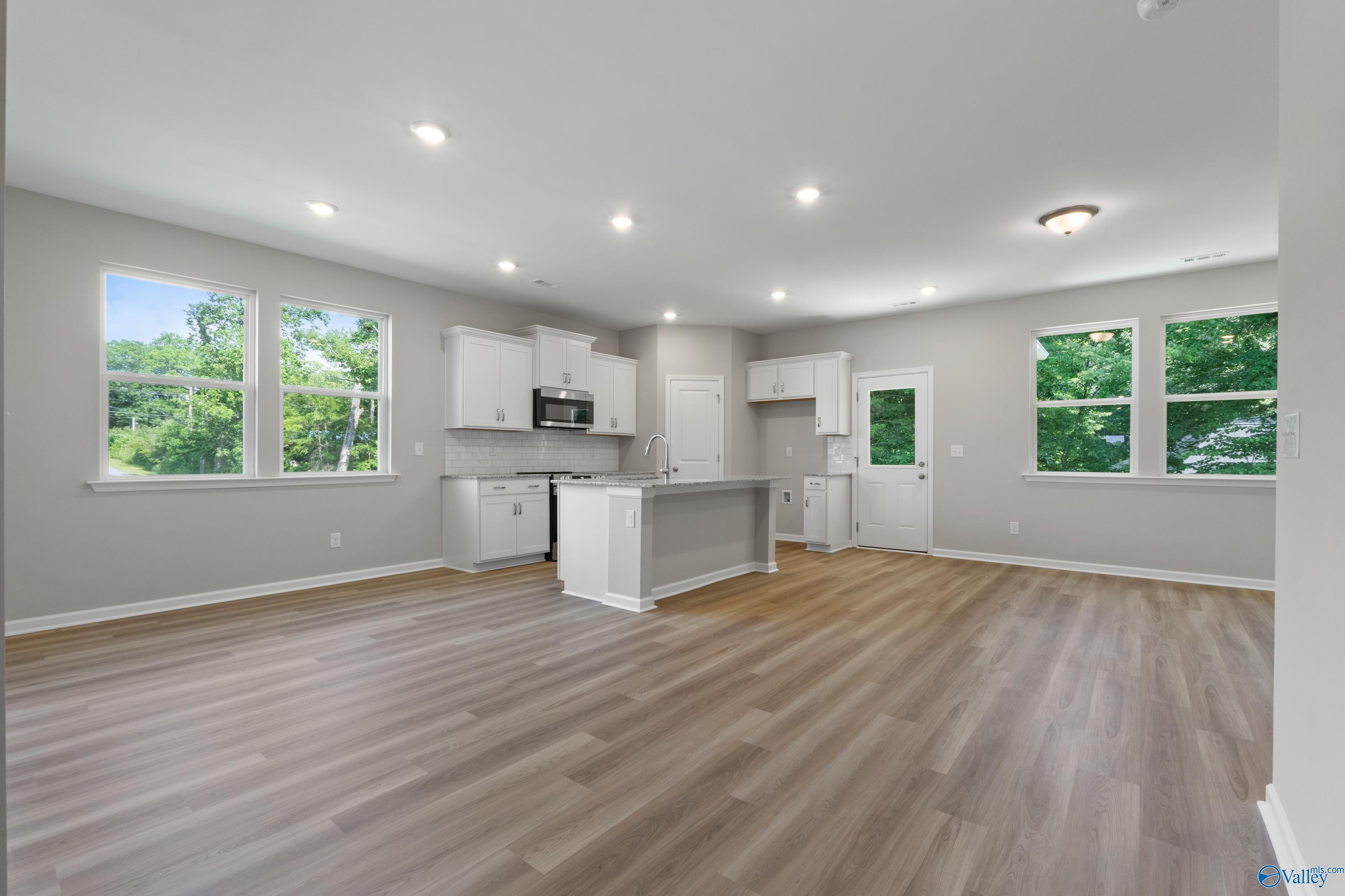 Modern open kitchen with white shaker cabinets, granite island, and large windows in The Polaris 3-bedroom home, Fayetteville, TN
