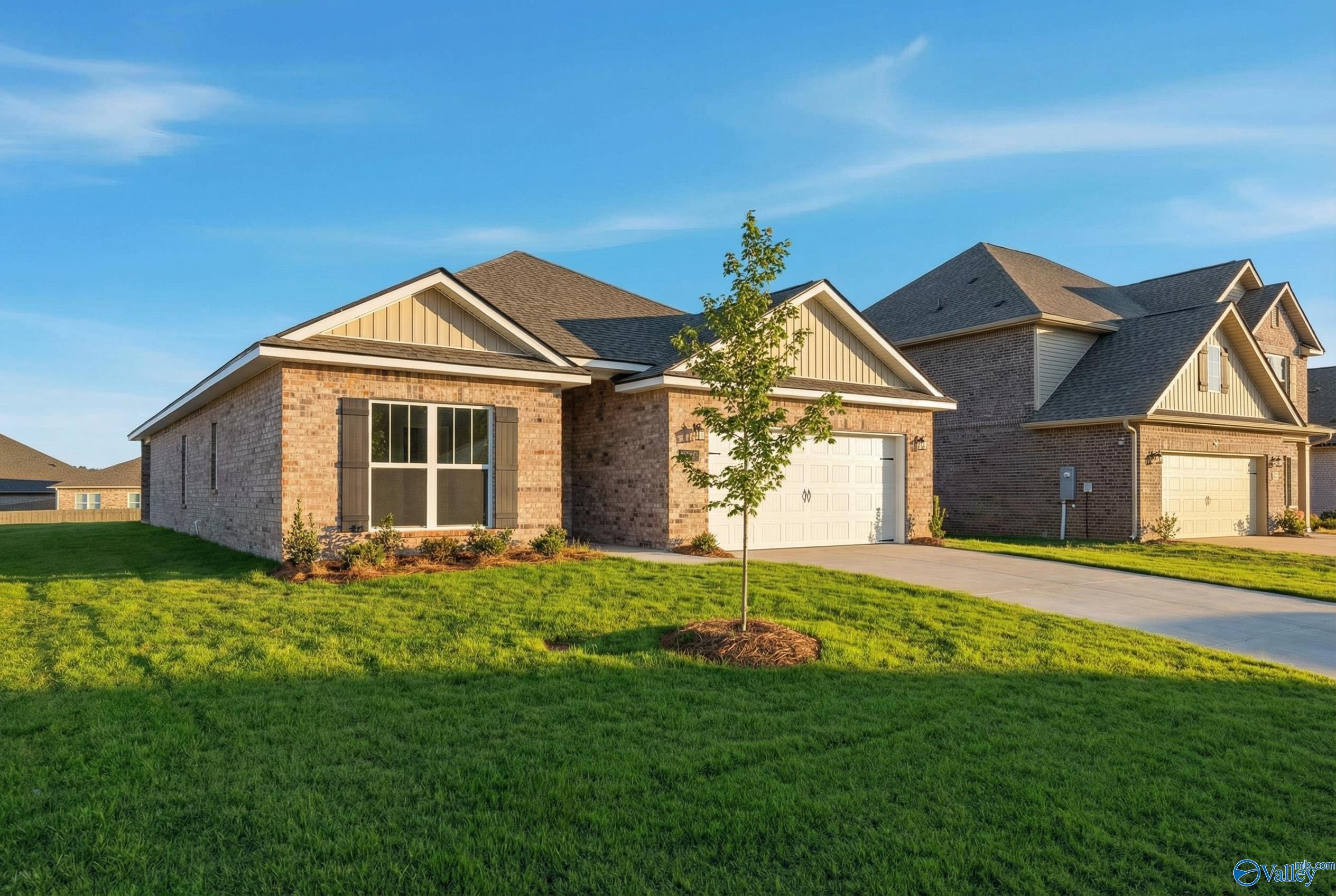 Brick single-story home with 2-car garage, young tree, lush lawn and driveway in Creekside, Harvest, Alabama - Davidson Homes The Everett