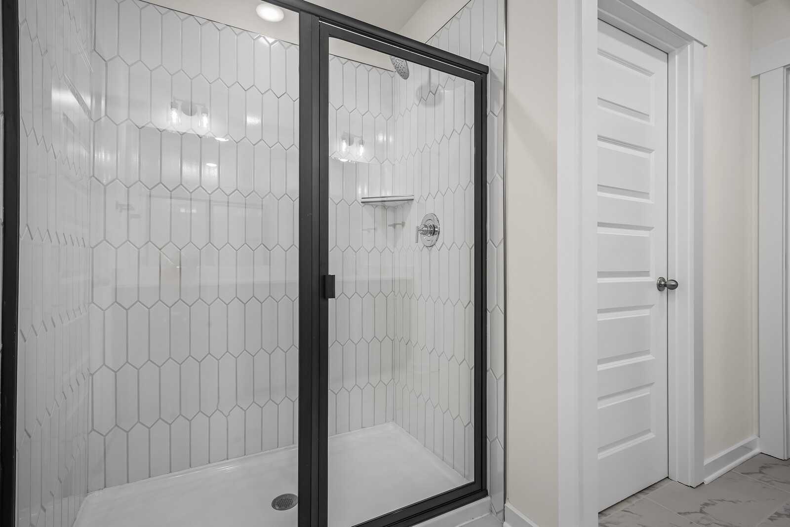 Modern walk-in shower with white subway tiles and black-framed glass door in Davidson Homes The Logan C, Gallatin, TN