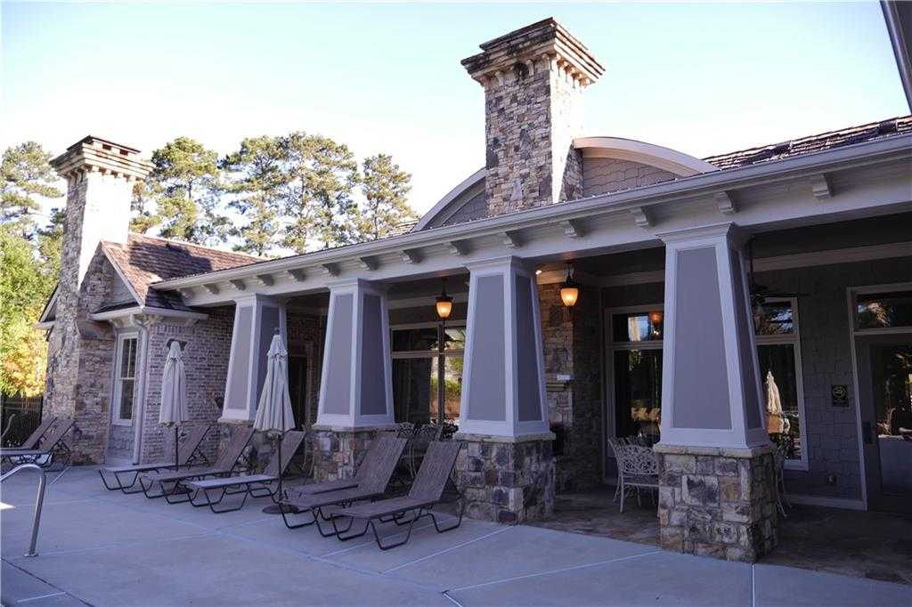 Covered poolside patio with chaise lounges, umbrellas, stone pillars, and chimneys in Davidson Homes The Seaside B, Woodstock, GA