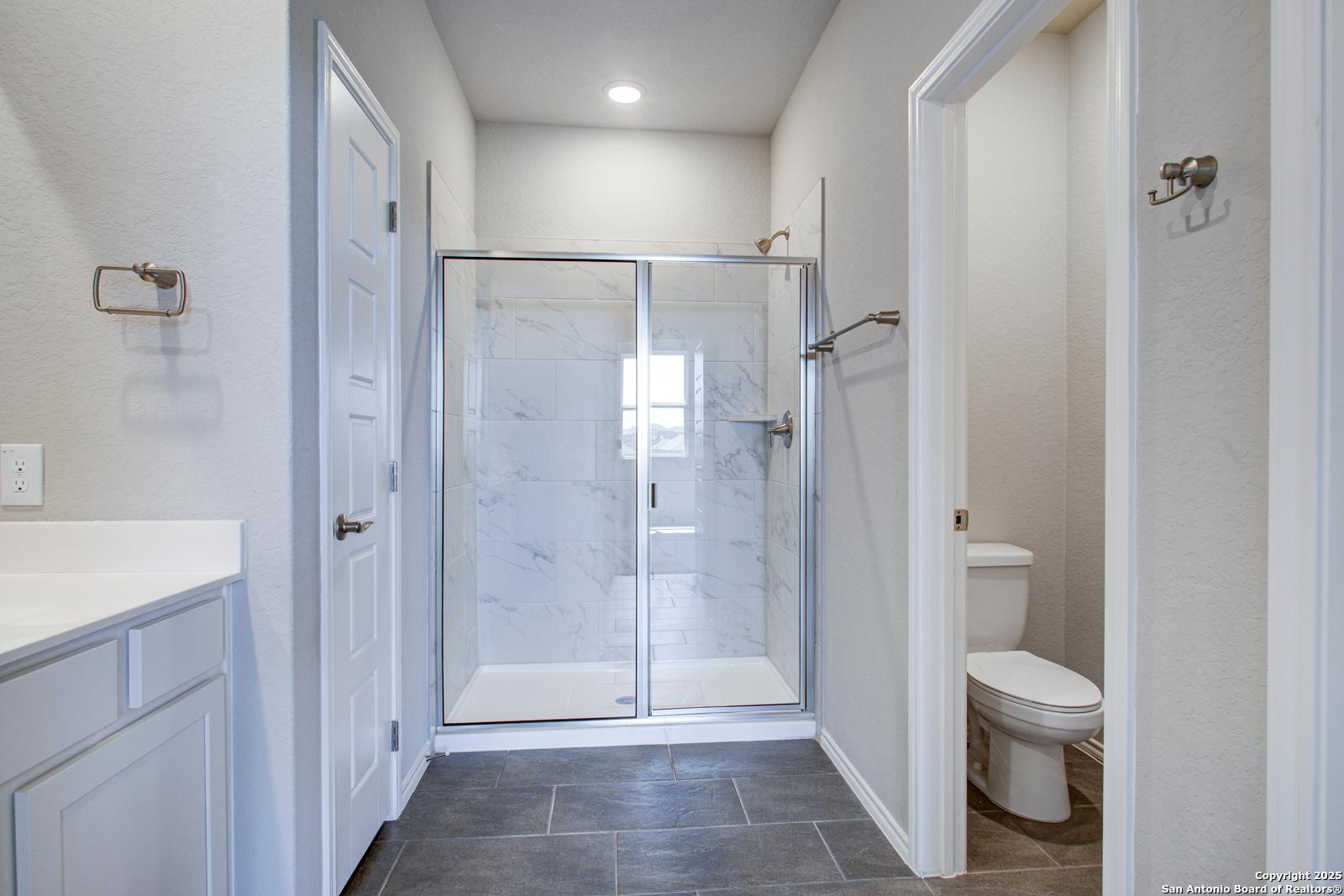 Modern master bathroom with frameless glass shower, white marble tile vanity, and subway walls in Davidson Homes The Douglas G, San Antonio