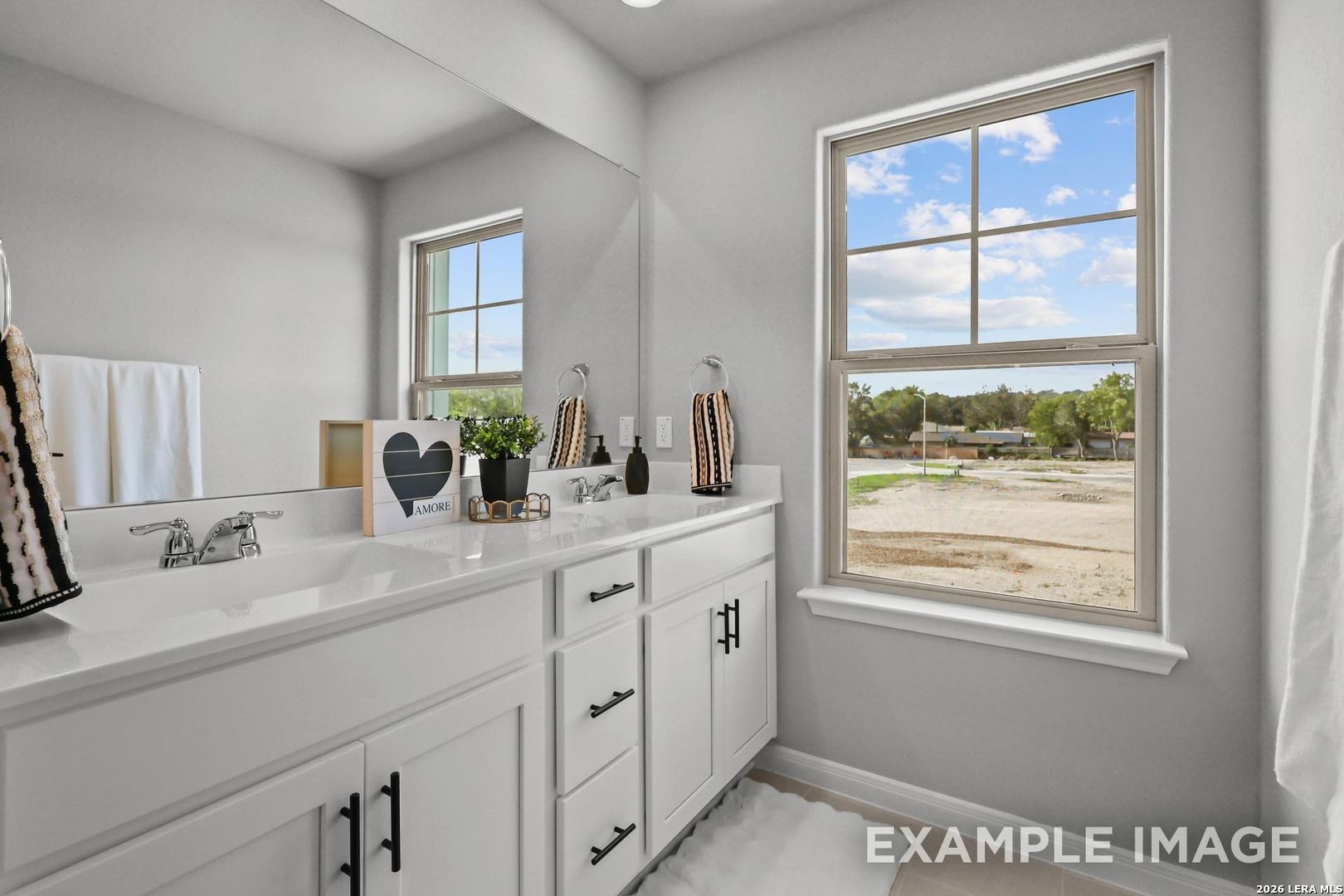 Modern bathroom with double vanity and large mirror in The Gillian A floor plan at Cedar Heights, San Antonio.