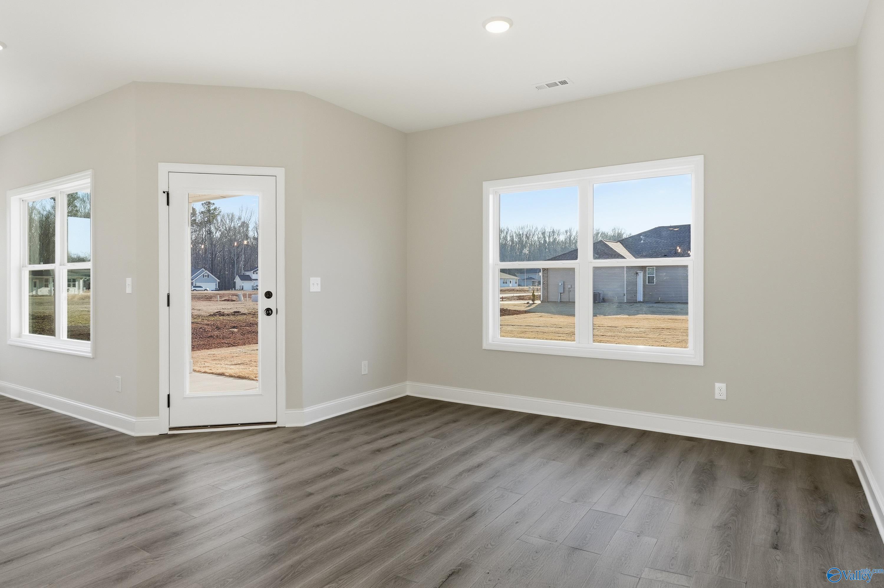 Bright flex room with beige walls, gray LVP flooring, French door and large windows in The Franklin E home, Hazel Green, AL