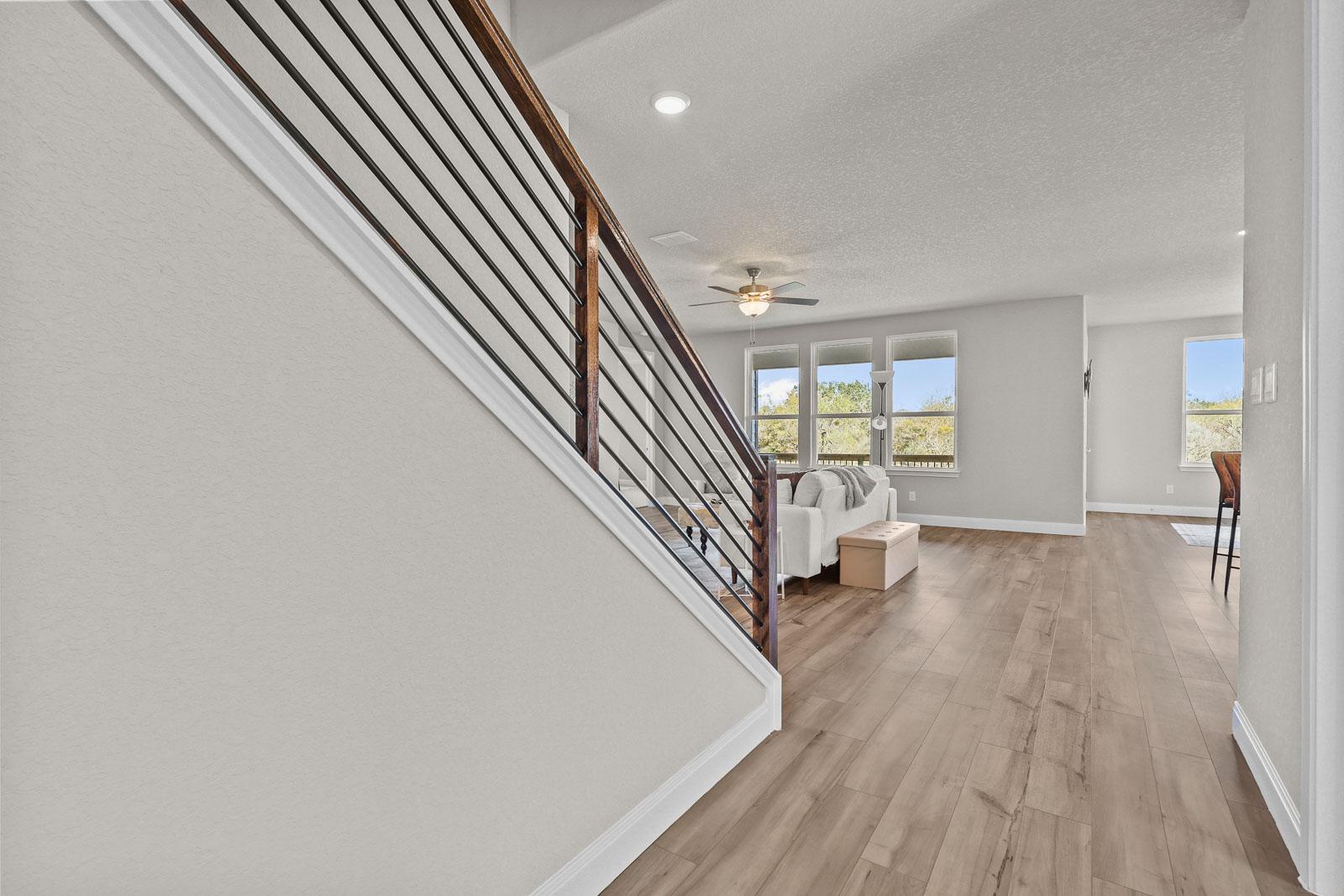 Modern staircase with wood railing in The Jennings G open-concept living area featuring light wood flooring.