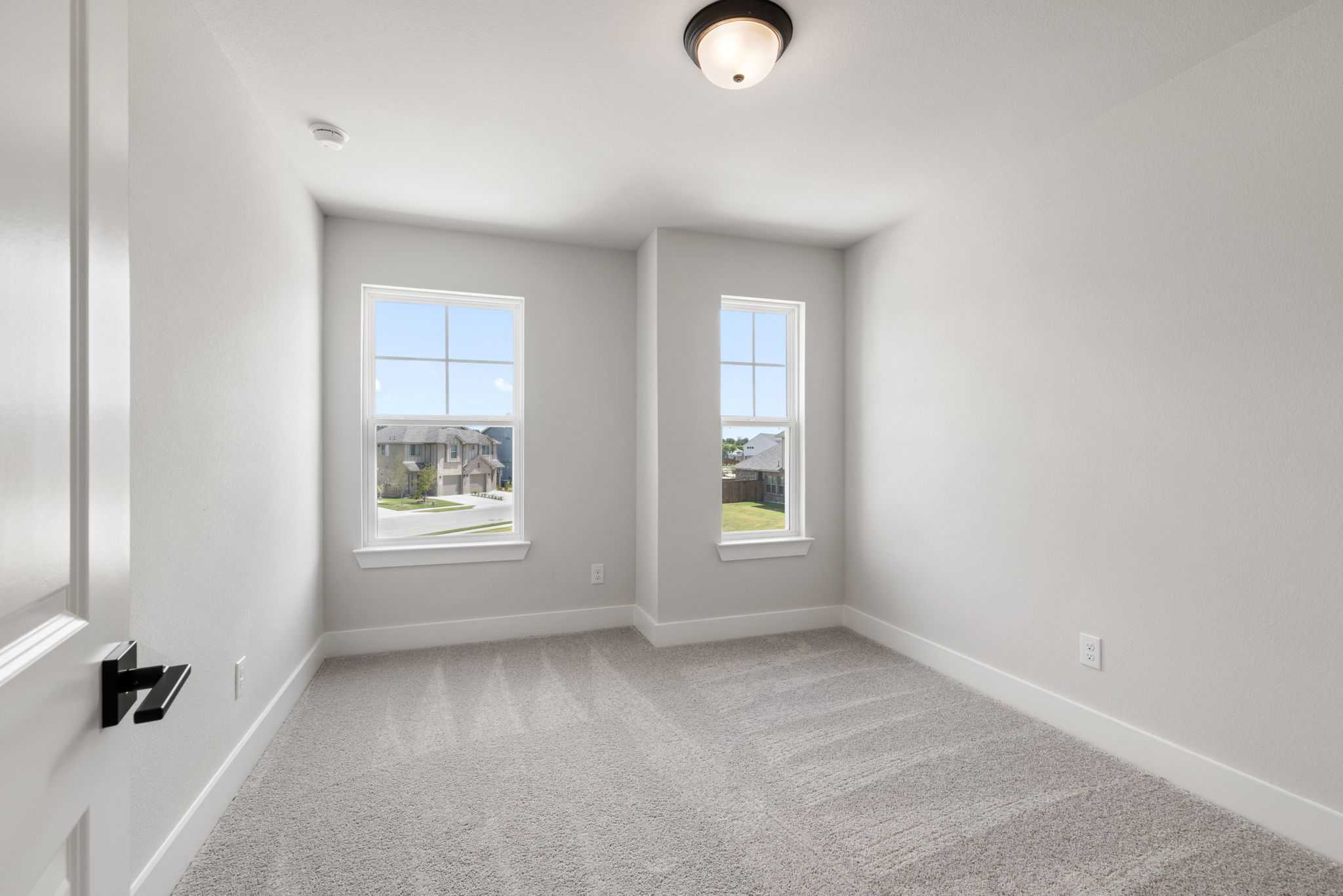 Bright secondary bedroom with large windows, gray carpet, and natural light in Davidson Homes The Durham E, Wylie, Texas