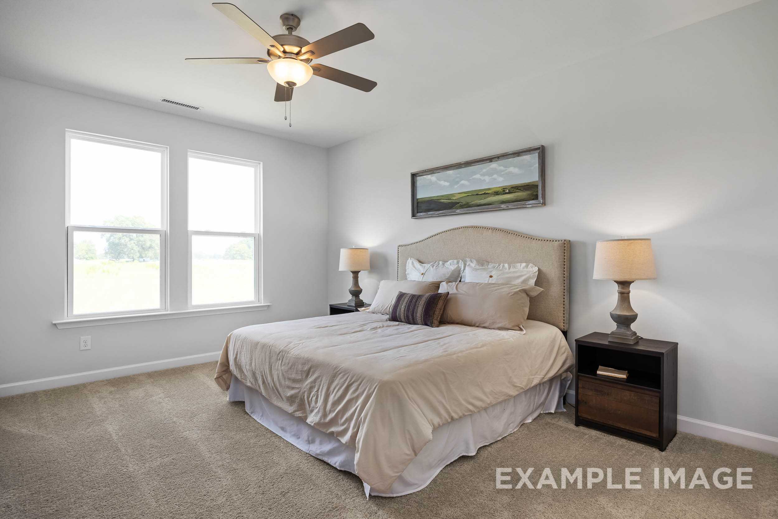 Spacious master bedroom in The Daphne C featuring king bed with neutral bedding, ceiling fan, lamps, and large windows