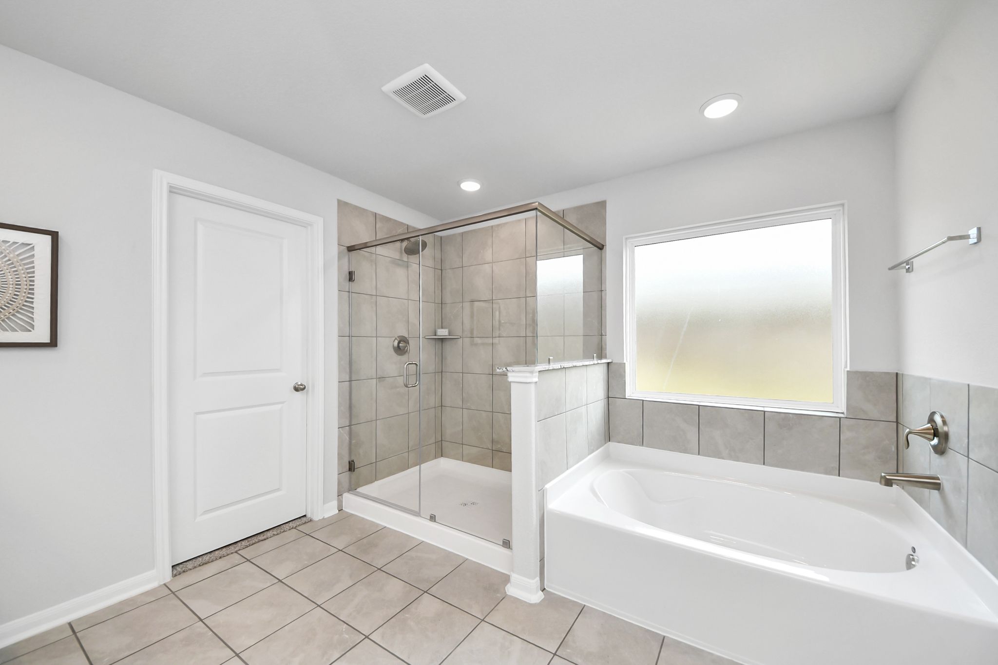 Primary bathroom with walk-in glass shower and soaking tub at Sunterra in Katy, TX by Davidson Homes.
