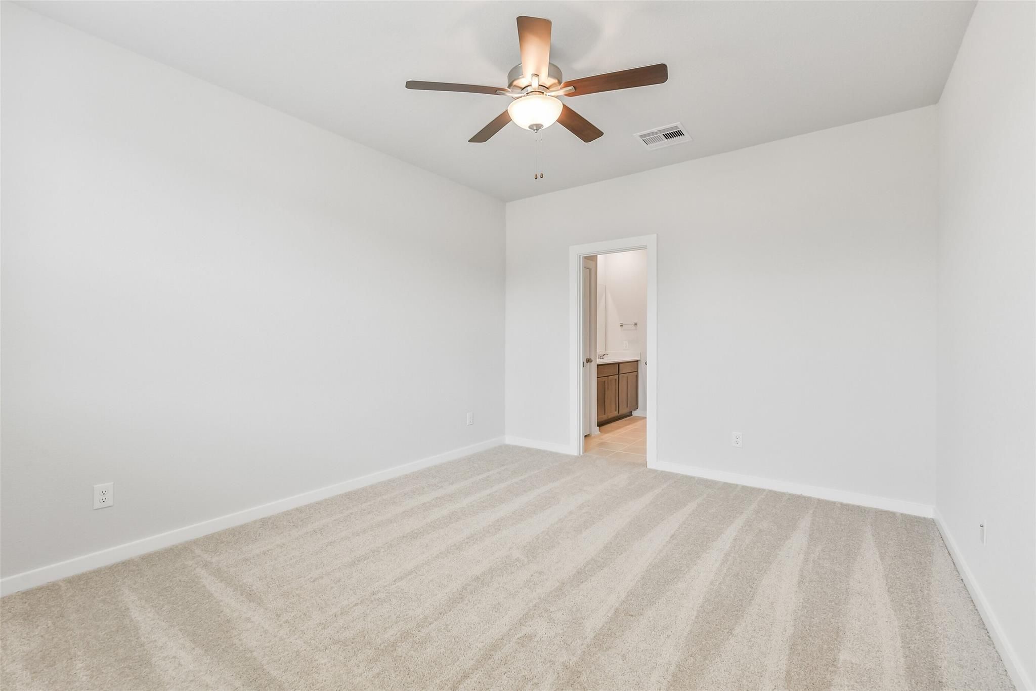 Bright bedroom with ceiling fan, white walls, and beige carpet in 5-bedroom The Brazos E home, Cleveland, TX