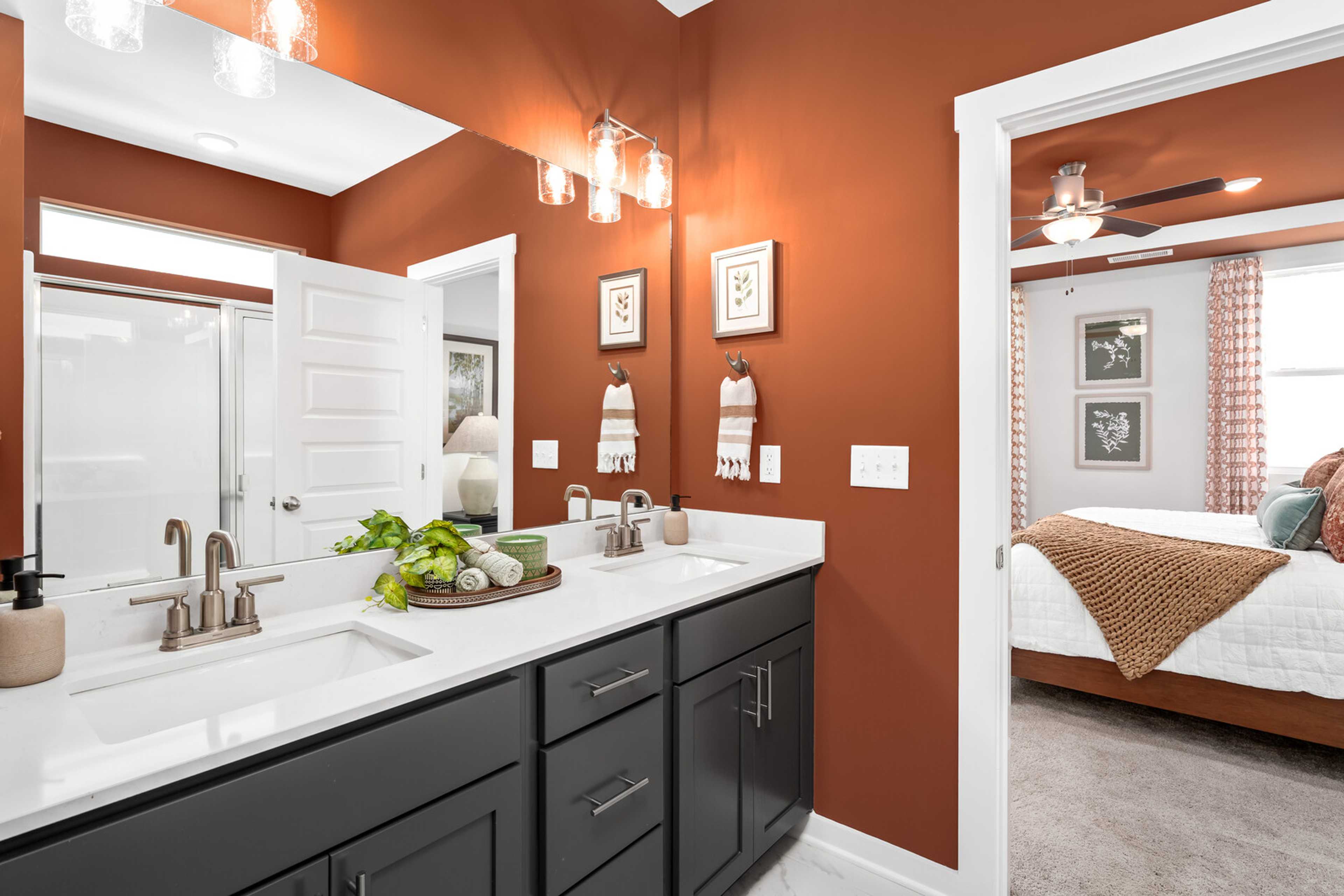Spacious master bathroom at Calista Farms in White House TN with double vanity, rust walls, plants, and adjacent bedroom view
