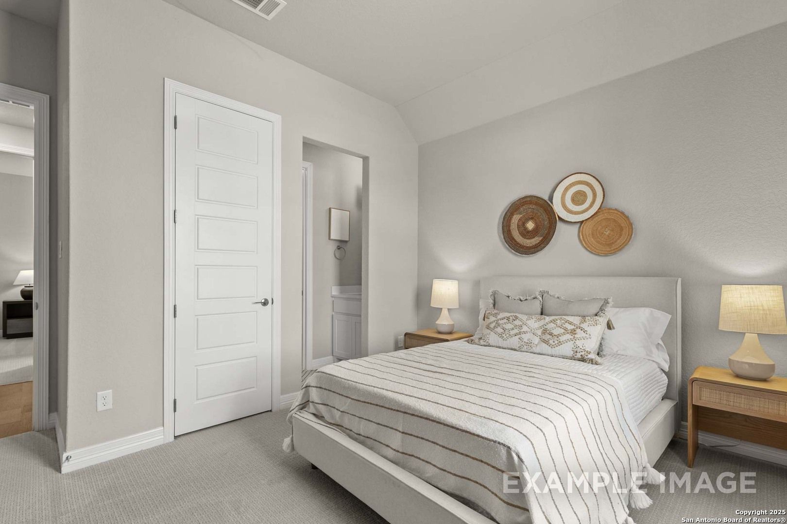 Cozy bedroom with gray walls, upholstered bed in striped linens, nightstands, lamps, and woven wall decor in Davidson Homes The Summerlin B, Castroville, Texas