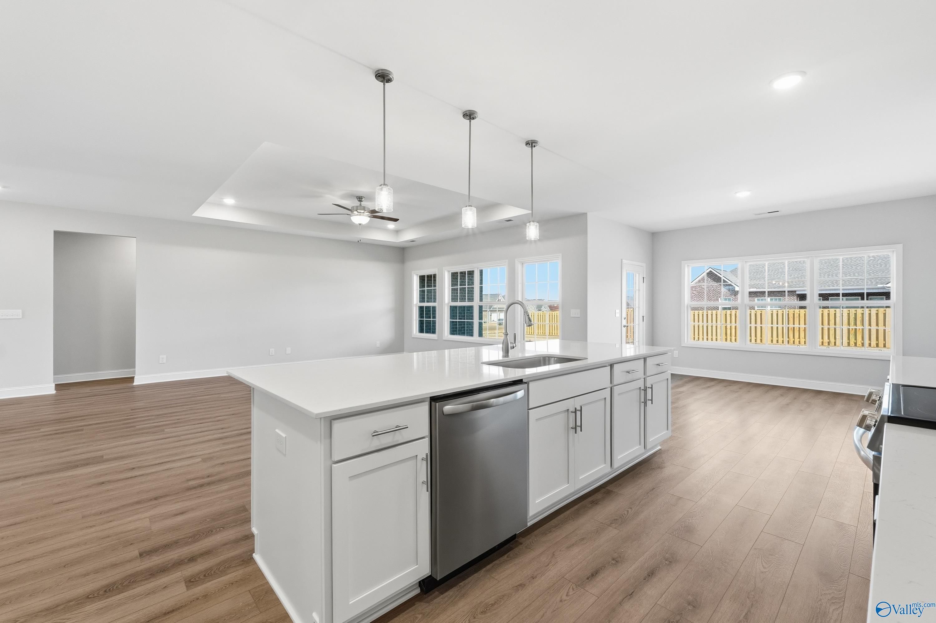 Modern open-concept kitchen with white island, stainless dishwasher, hardwood floors in Davidson Homes The Finleigh, Harvest, AL