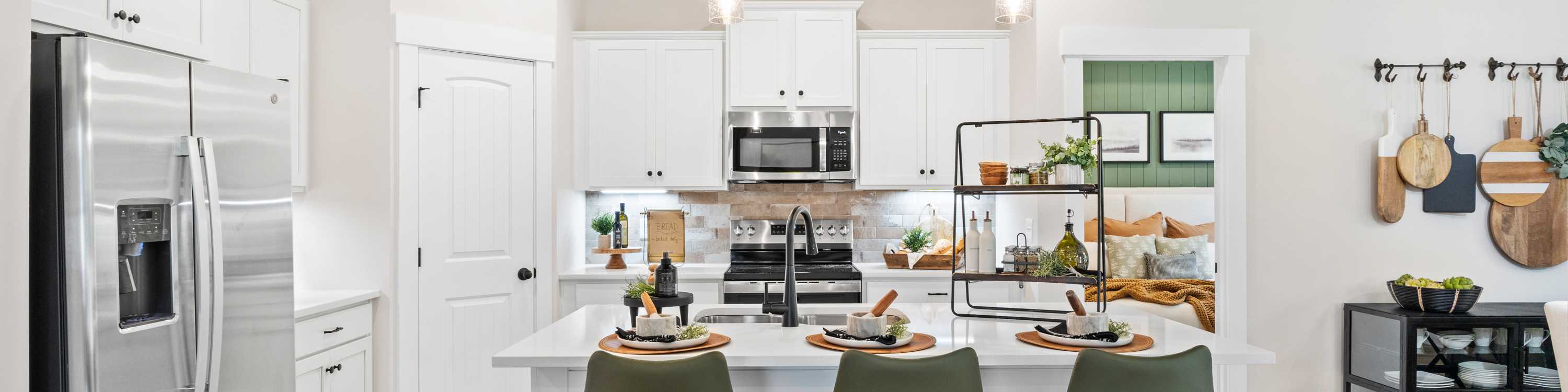 Spacious modern kitchen in Spragins Cove Huntsville AL with white island, green barstools, stainless appliances, hardwood floors