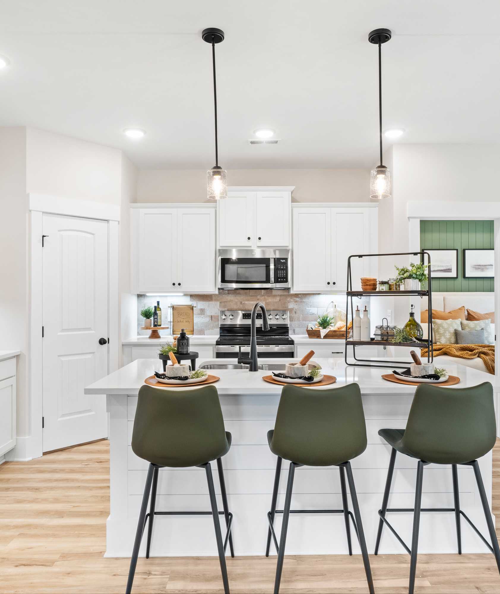 Spacious modern kitchen in Spragins Cove Huntsville AL with white island, green barstools, stainless appliances, hardwood floors
