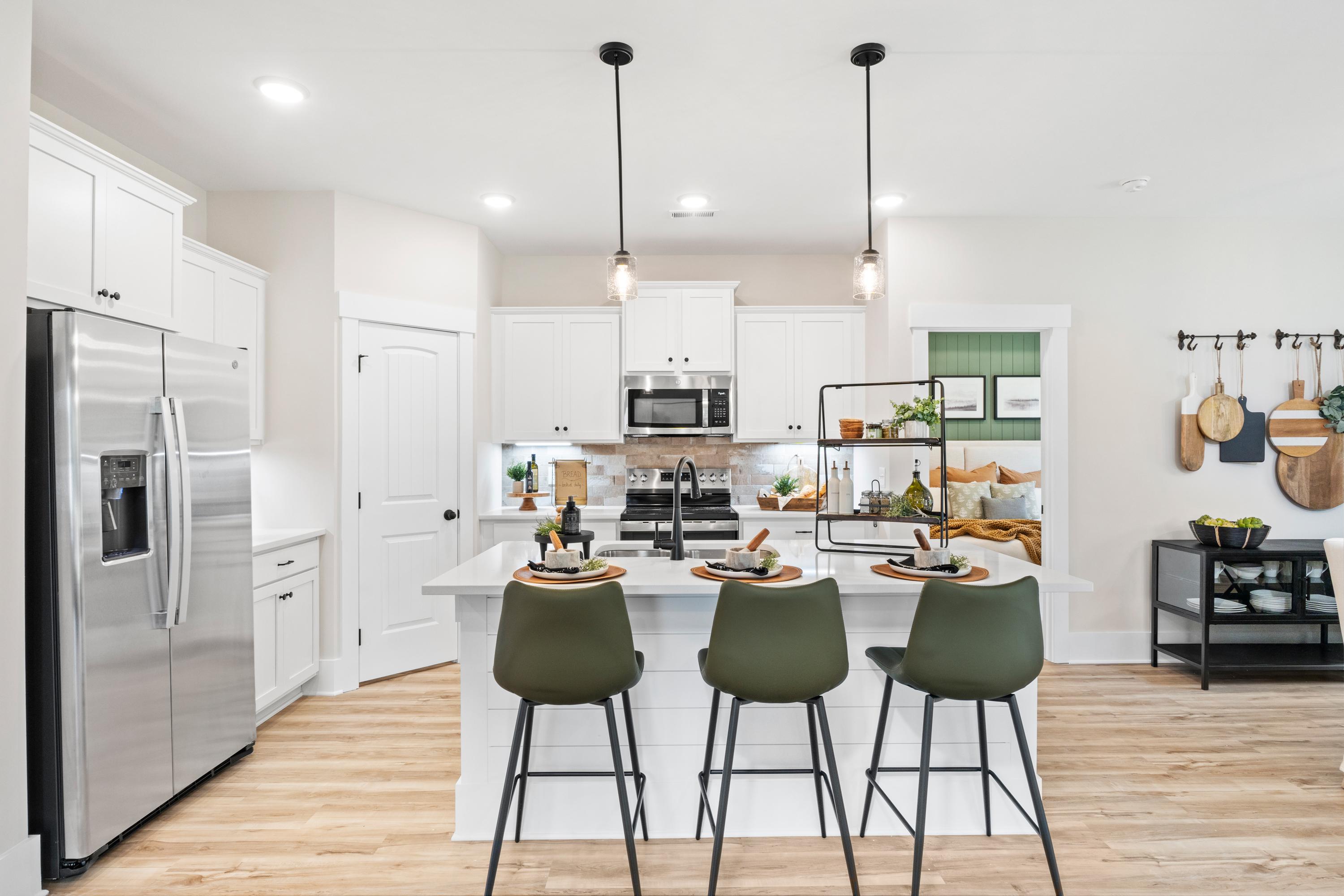 Spacious modern kitchen in Spragins Cove Huntsville AL with white island, green barstools, stainless appliances, hardwood floors