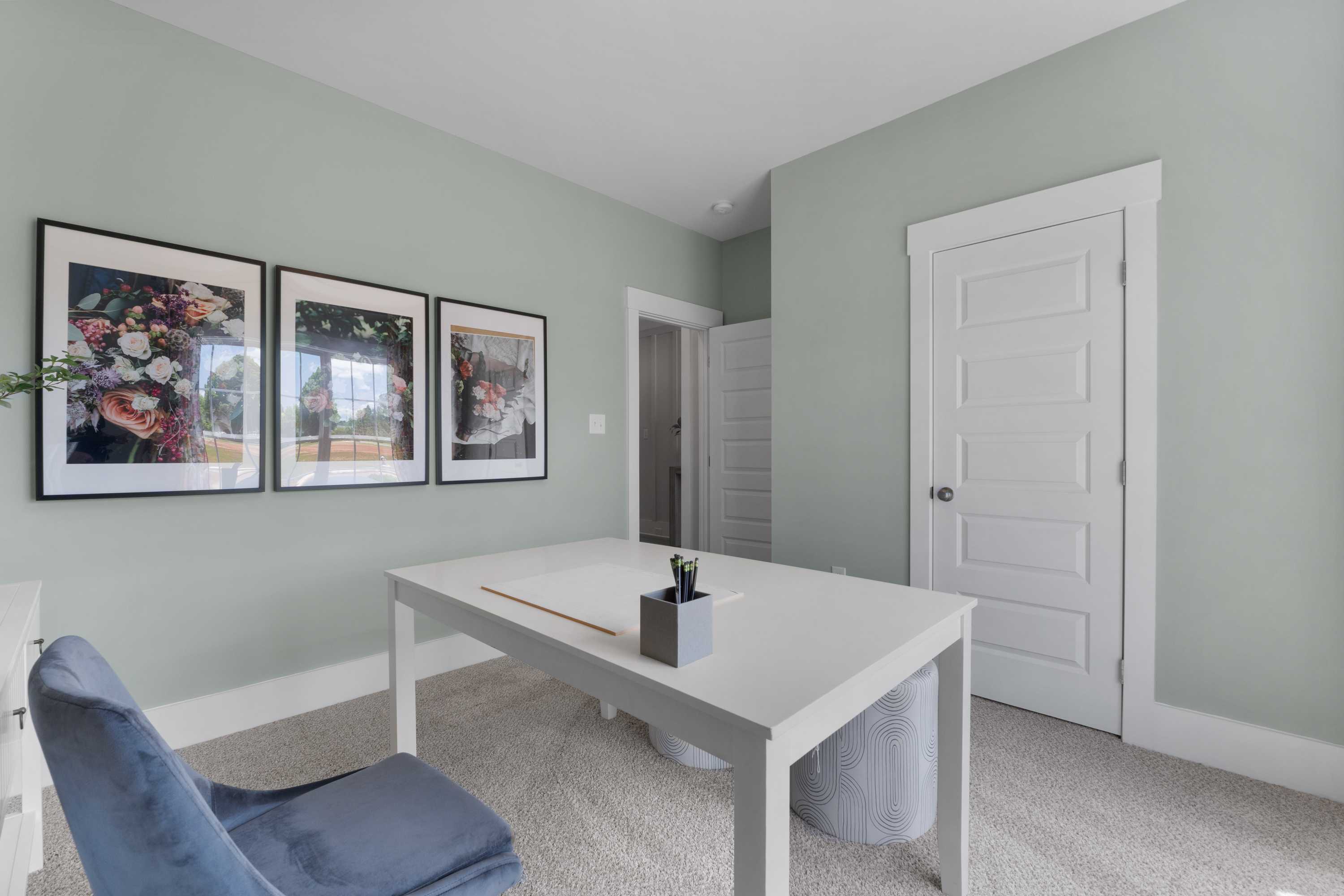 Cozy home office in Hollon Meadow Decatur AL with sage green walls, white desk, blue chair, and floral art prints