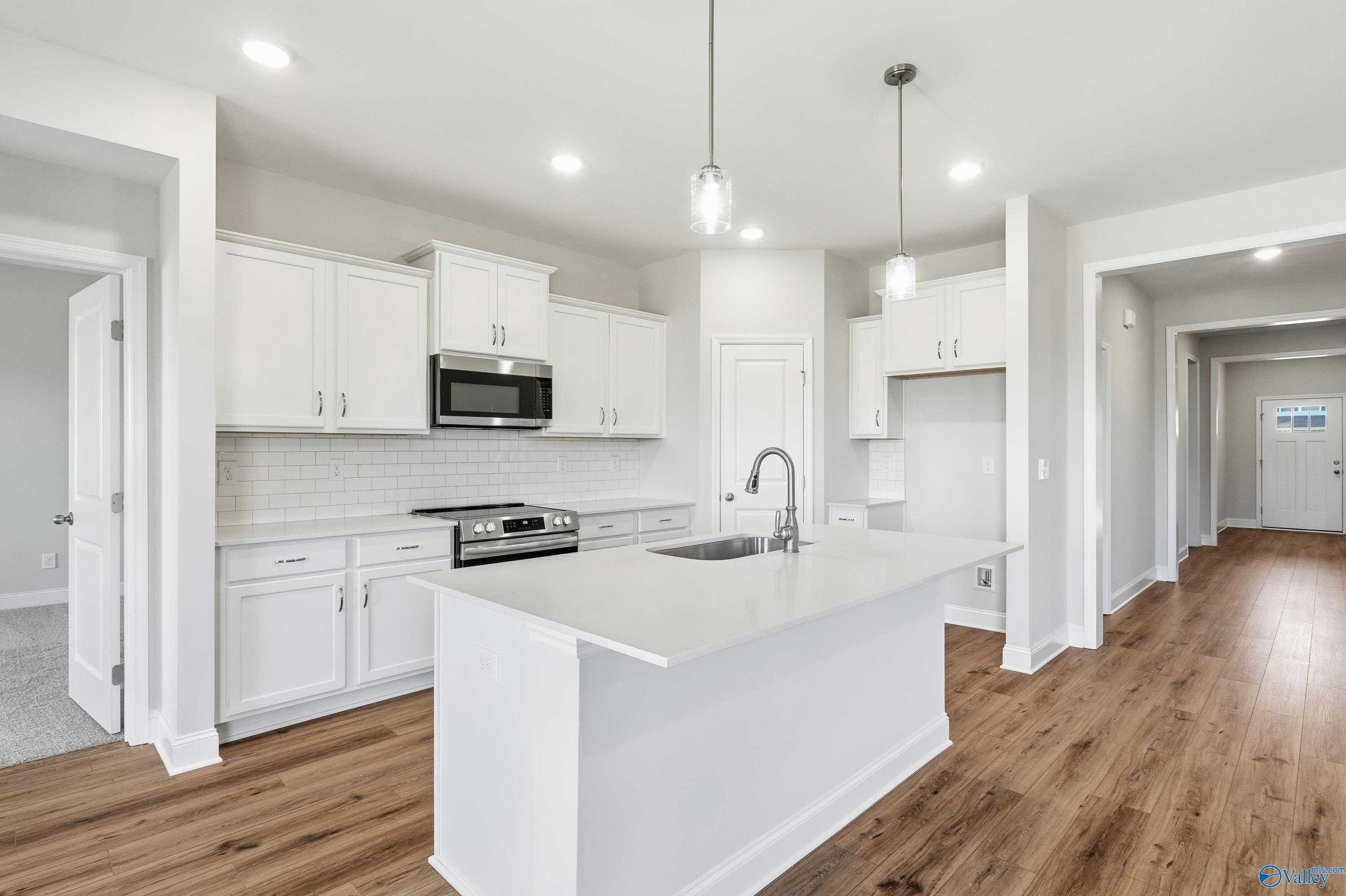 Bright white kitchen with large island, stainless steel appliances, subway tile backsplash in Davidson Homes The Everett, Harvest AL