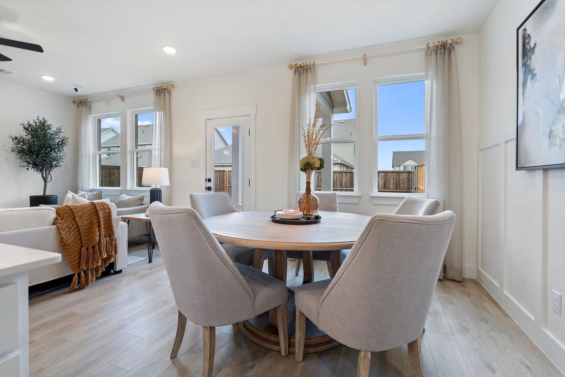 Elegant round dining table with gray chairs and pampas centerpiece in open living area of The Wake D home, Lake Park Villas, Wylie, Texas