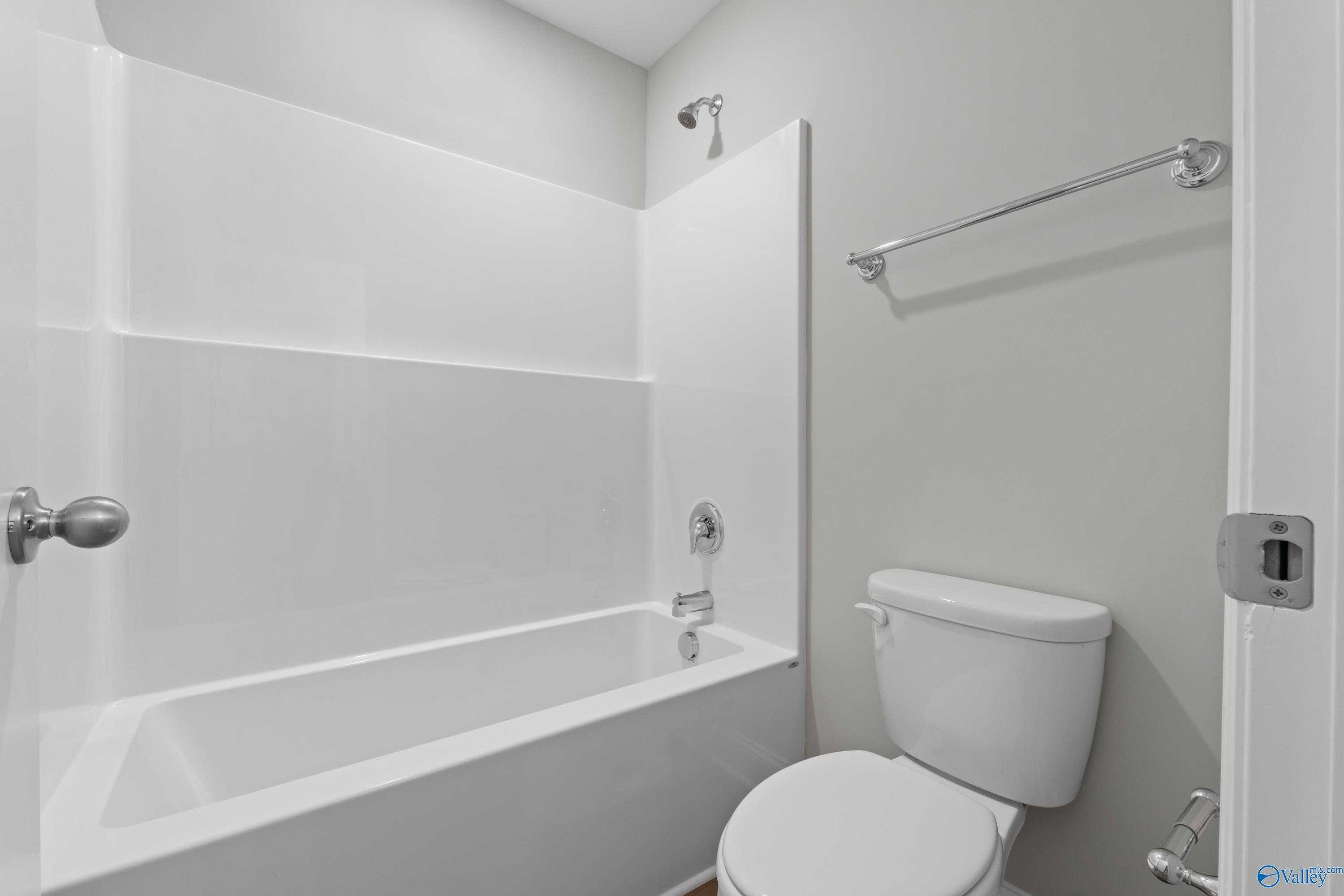 Modern white bathtub and toilet in spacious bathroom with gray walls, Davidson Homes Chelsea B, New Market, Alabama