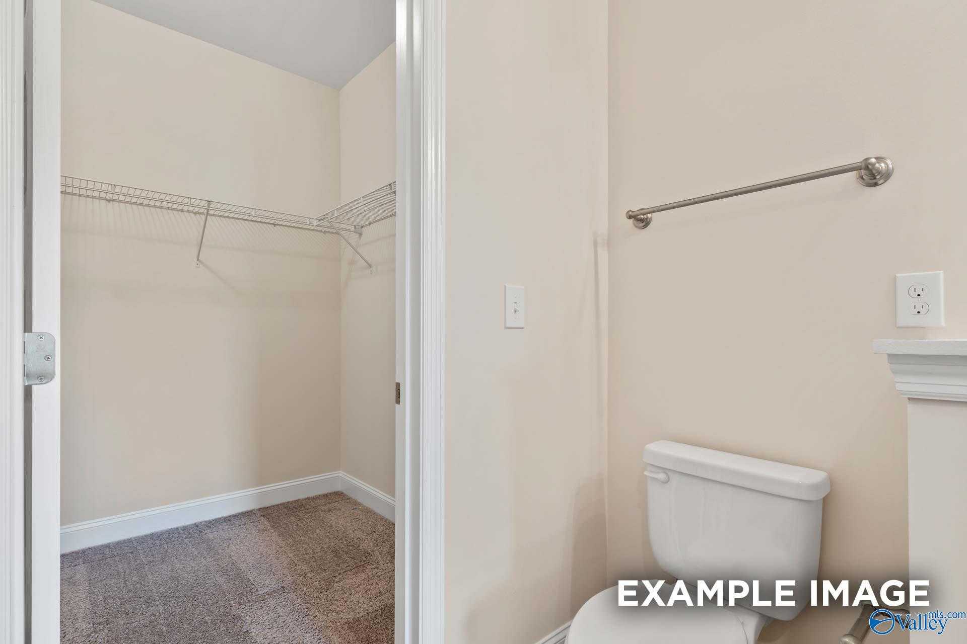 Walk-in closet with wire shelving and hanging rod beside bathroom with white toilet in The Asheville 3-bedroom home, Davidson Homes, Arab, AL