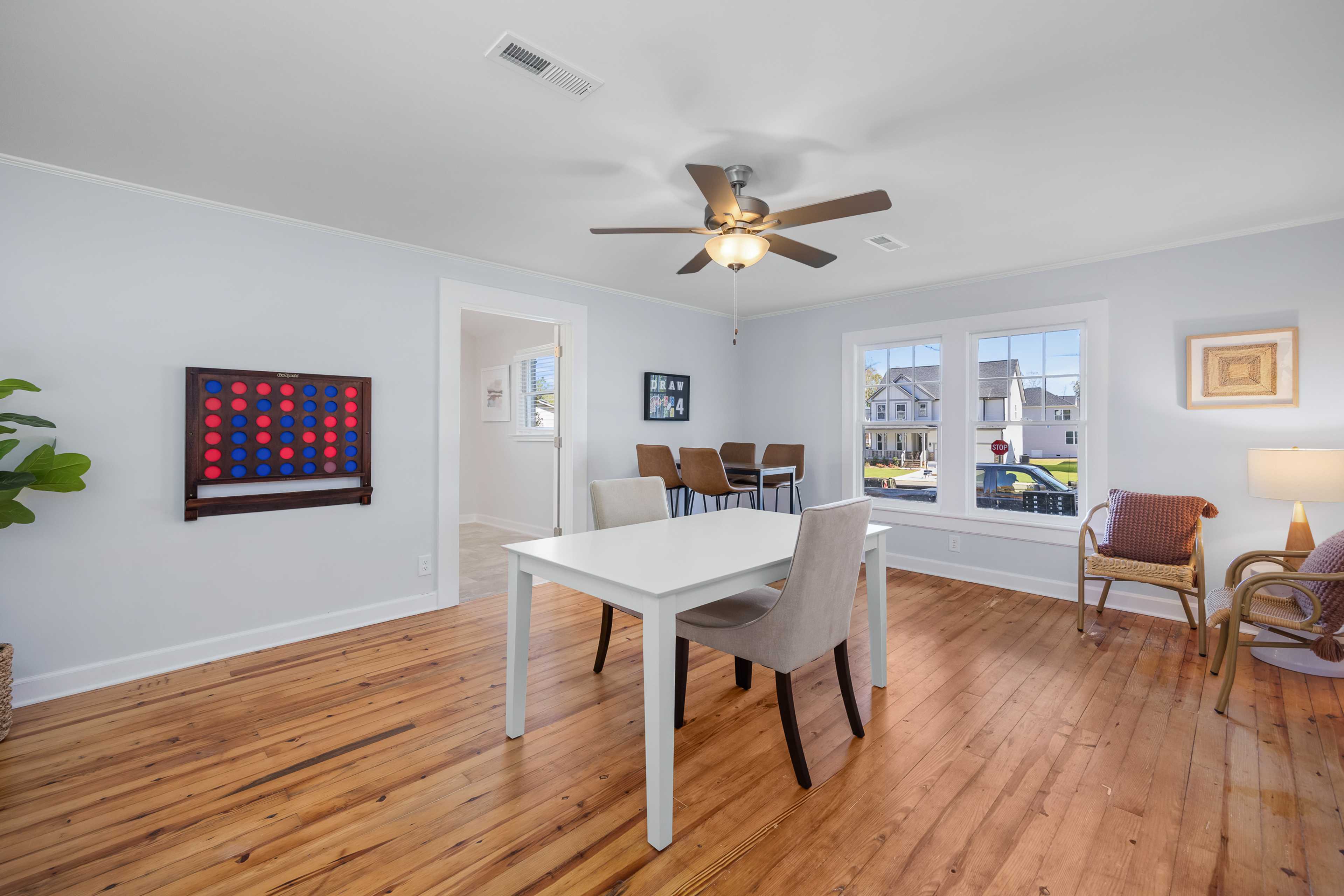 Dining room at Stagecoach Corner in Mebane NC by Davidson Homes with oak hardwood floors, white table, ceiling fan, and neighborhood window views