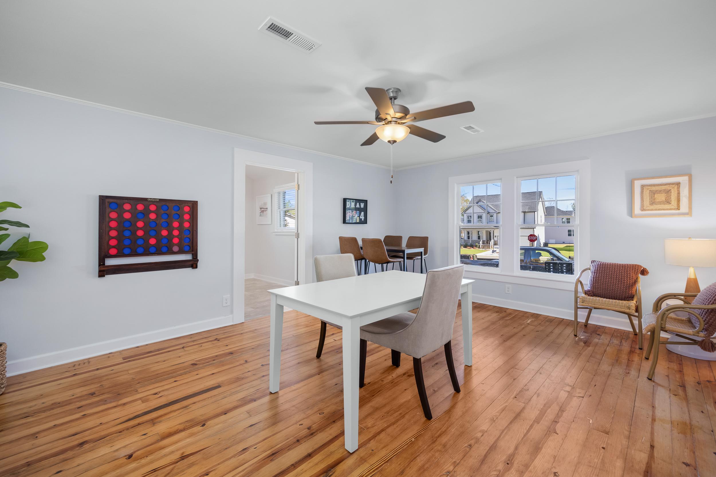 Dining room at Stagecoach Corner in Mebane NC by Davidson Homes with oak hardwood floors, white table, ceiling fan, and neighborhood window views