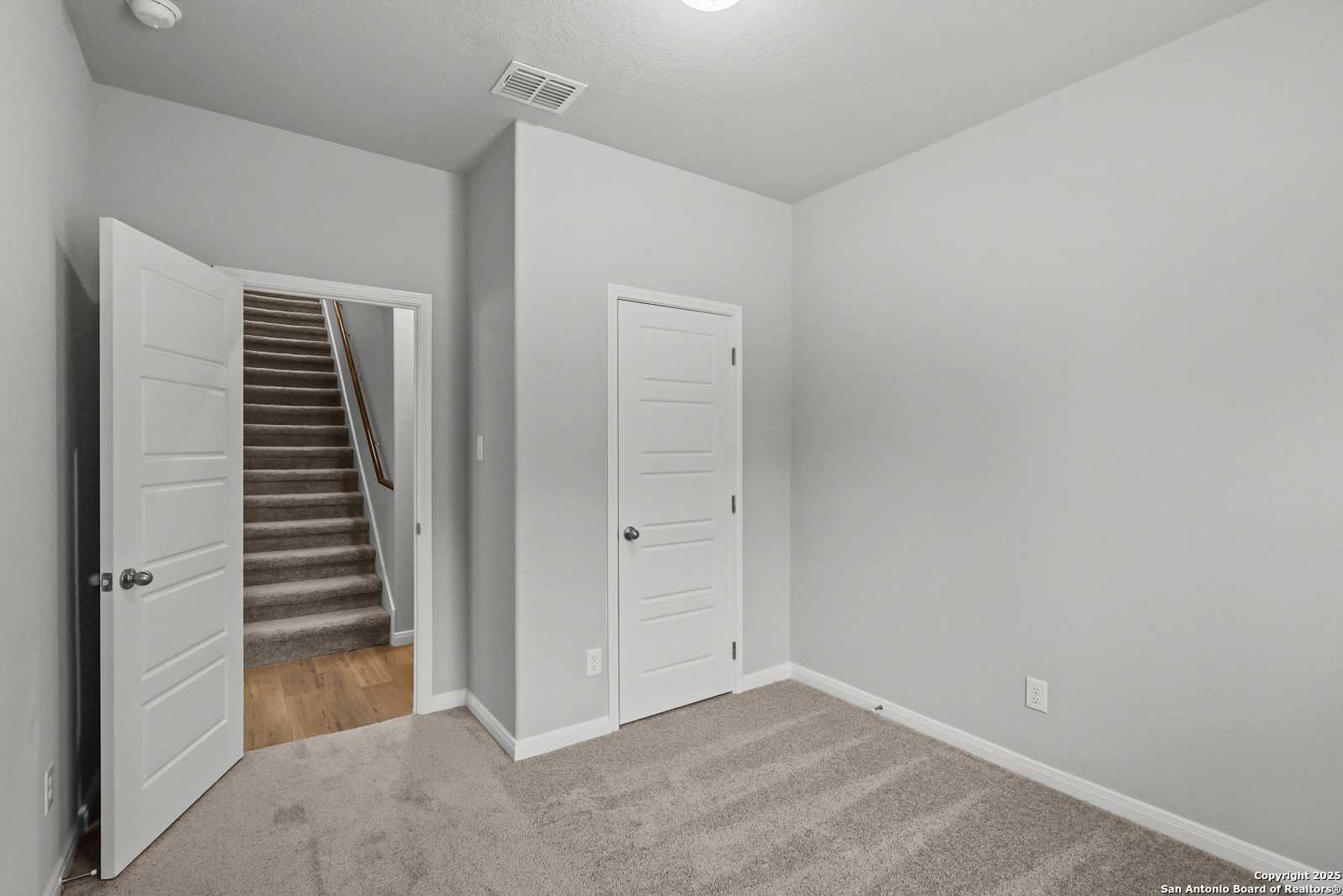 Upstairs landing with open door to carpeted staircase and adjacent bedroom door in Davidson Homes The Gillian C, San Antonio
