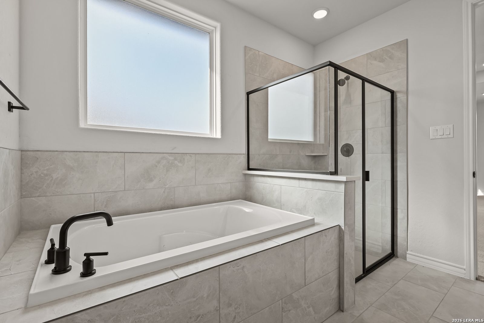Modern master bathroom with soaking tub, glass walk-in shower, and matte black fixtures in Davidson Homes The Oxford F, Castroville, TX
