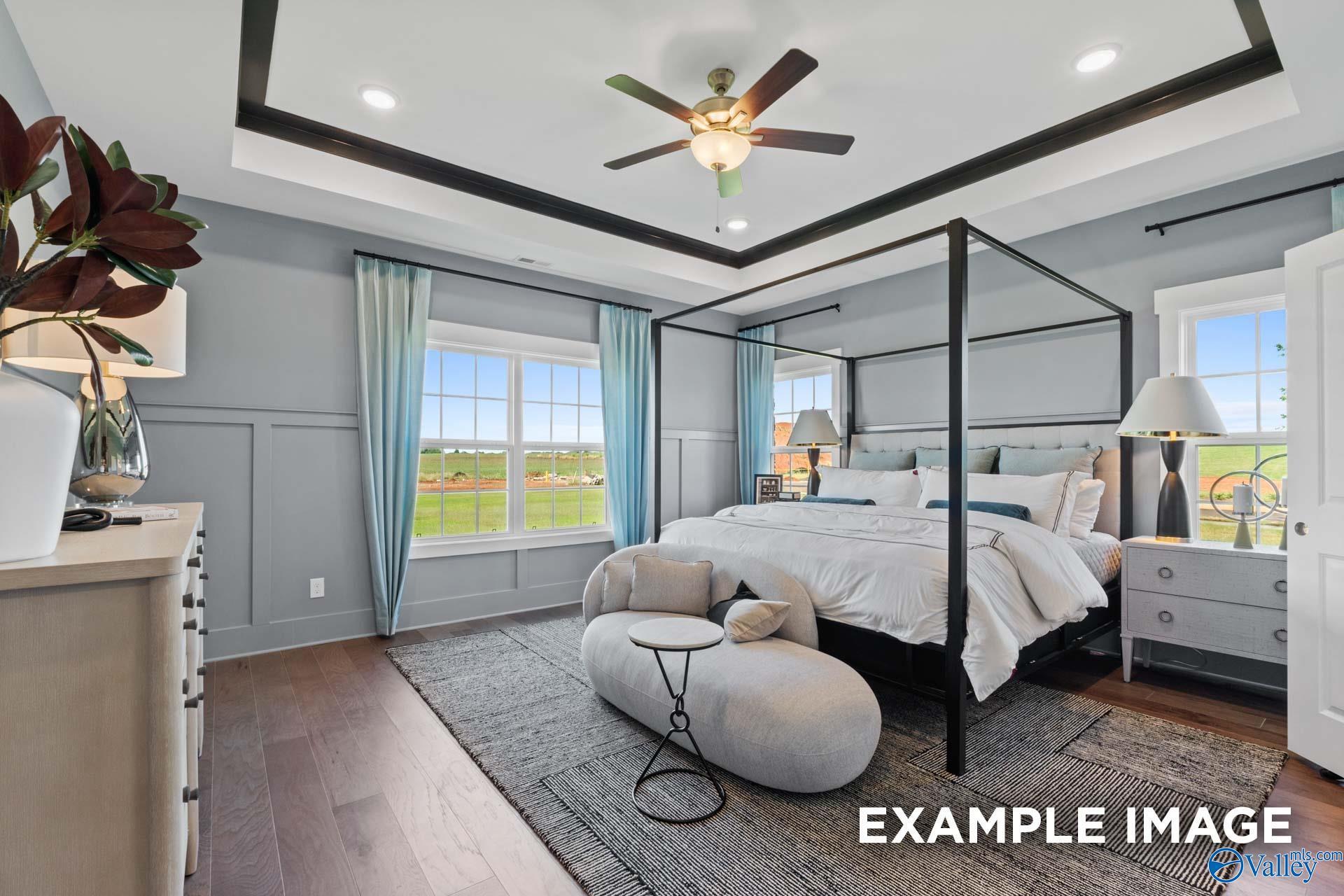 Elegant master bedroom with canopy bed, tray ceiling fan, and window view in Davidson Homes The Finleigh, Huntsville, AL
