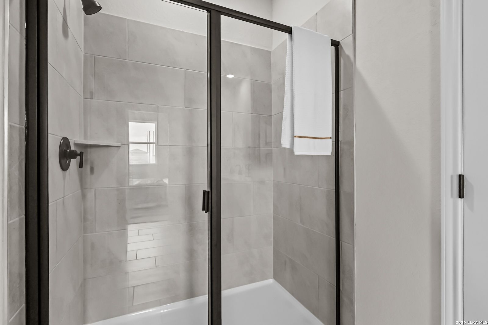 Walk-in shower with modern tile surround and black frame glass door in The Douglas C floor plan, Hannah Heights, Seguin.