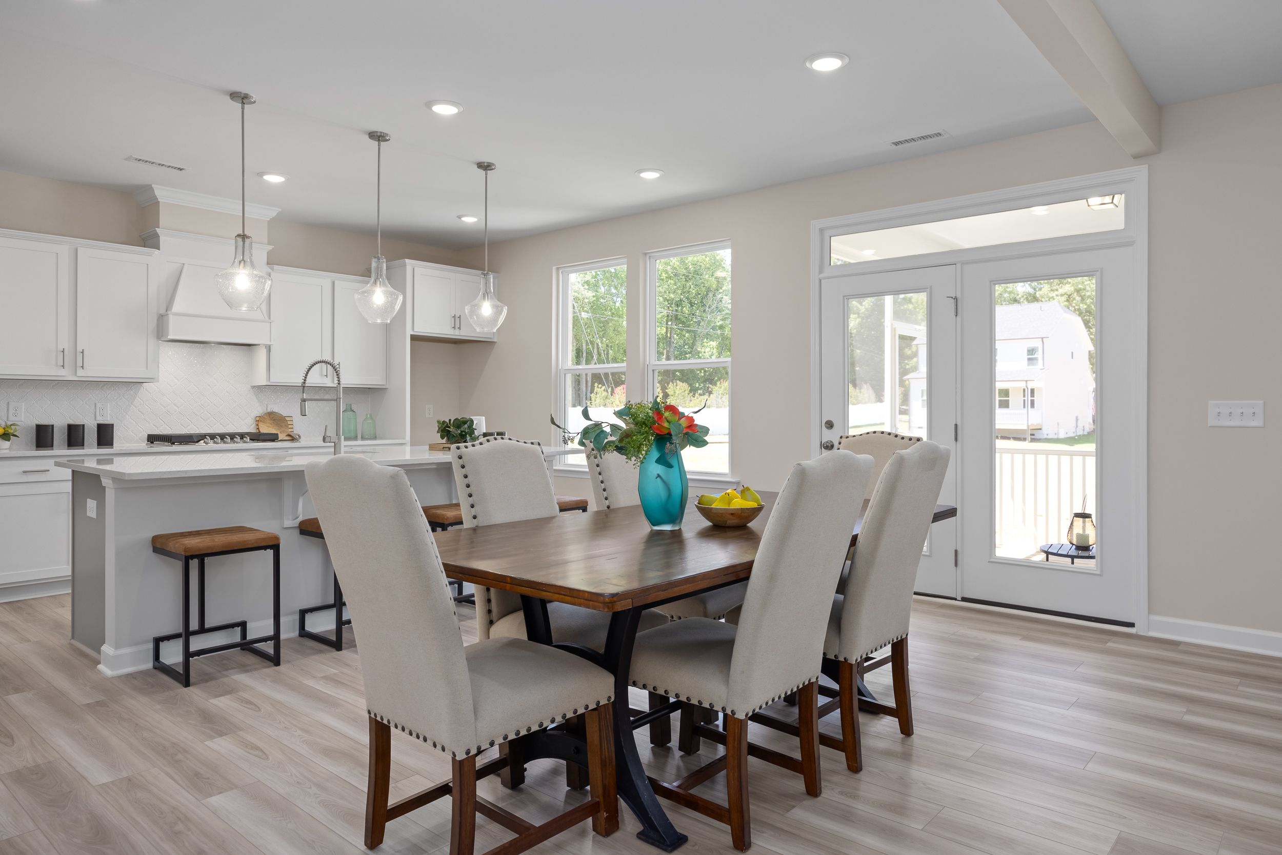 Open-concept kitchen and dining at Stagecoach Corner in Mebane NC with white cabinets, farmhouse island, wooden table, and French doors