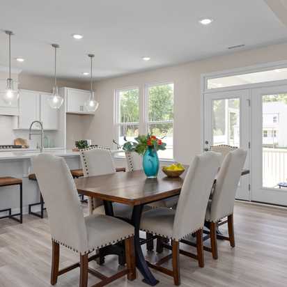 Open-concept kitchen and dining at Stagecoach Corner in Mebane NC with white cabinets, farmhouse island, wooden table, and French doors