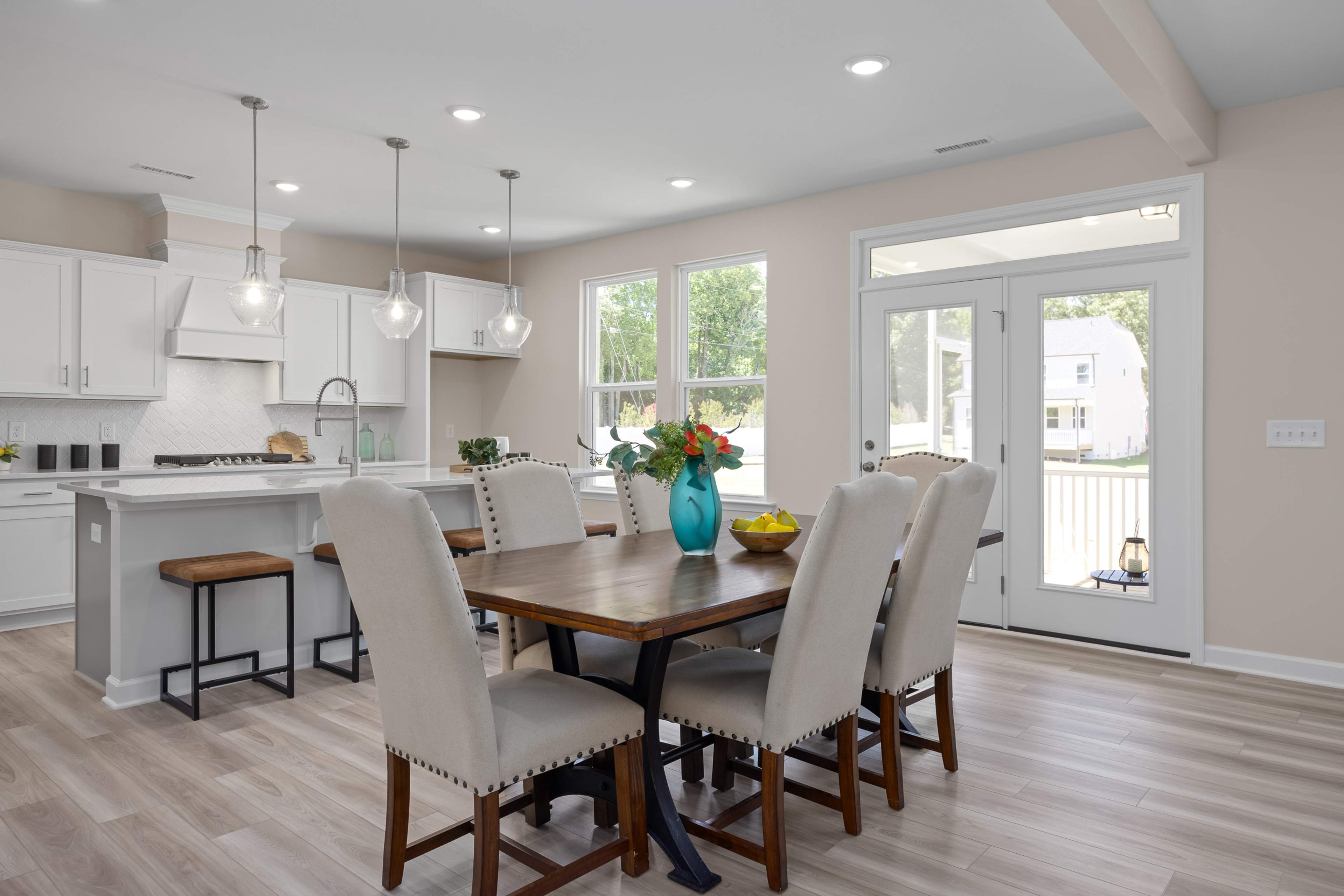 Open-concept kitchen and dining at Stagecoach Corner in Mebane NC with white cabinets, farmhouse island, wooden table, and French doors