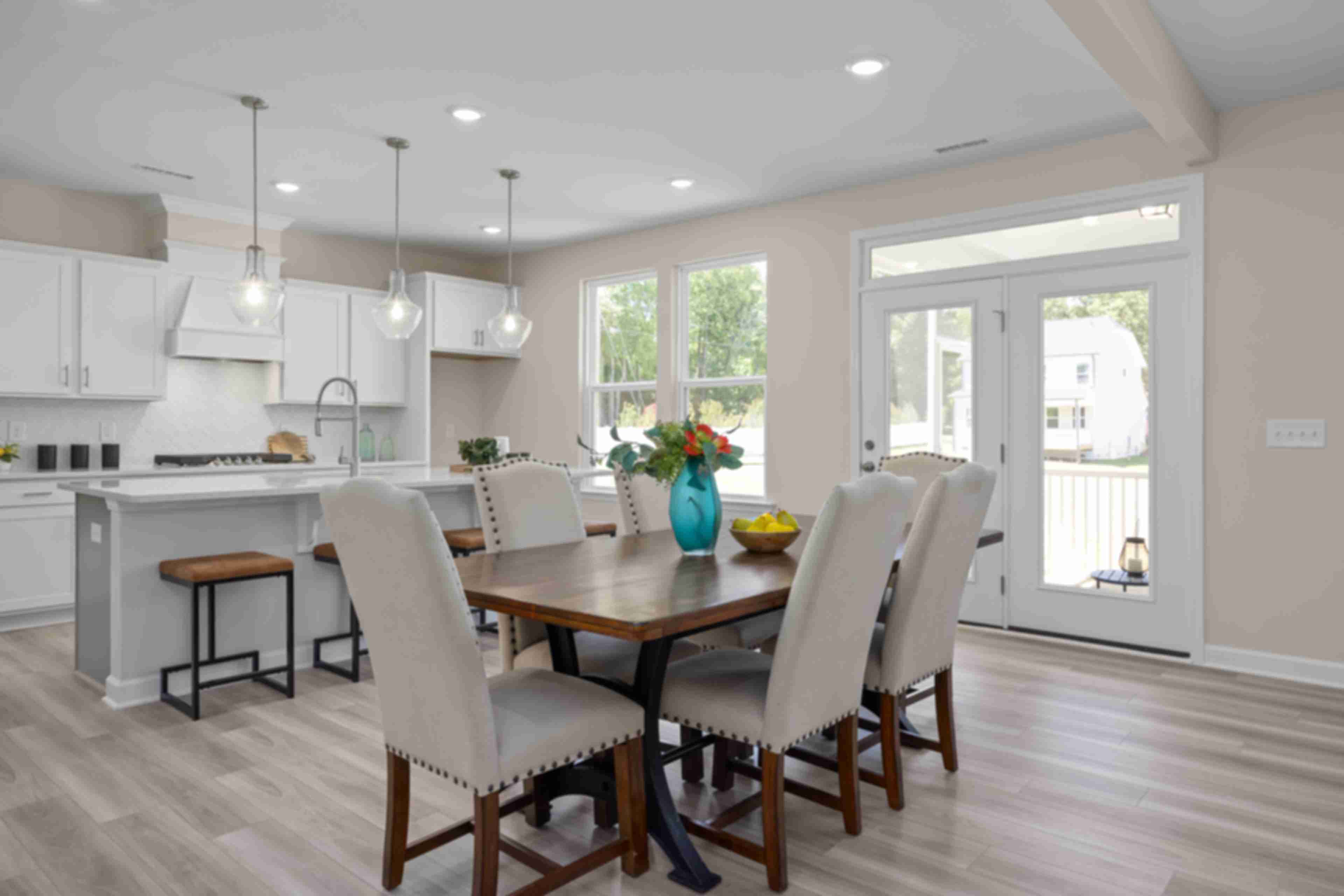 Open-concept kitchen and dining at Stagecoach Corner in Mebane NC with white cabinets, farmhouse island, wooden table, and French doors