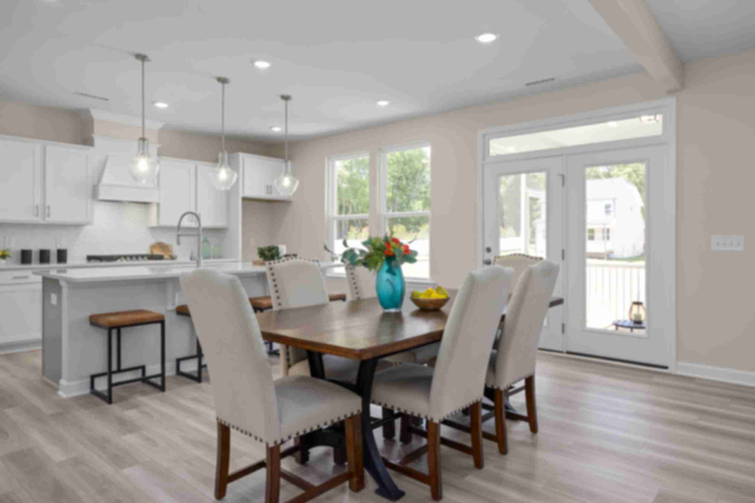 Open-concept kitchen and dining at Stagecoach Corner in Mebane NC with white cabinets, farmhouse island, wooden table, and French doors