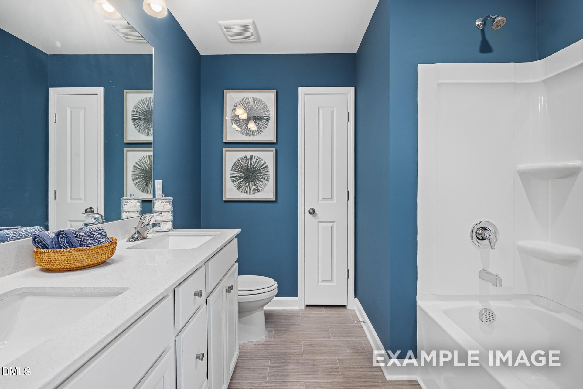 Modern bathroom with blue walls, dual vanity, and shower-tub combo in The Adalynn A floor plan at Woodland Crossing, Zebulon.