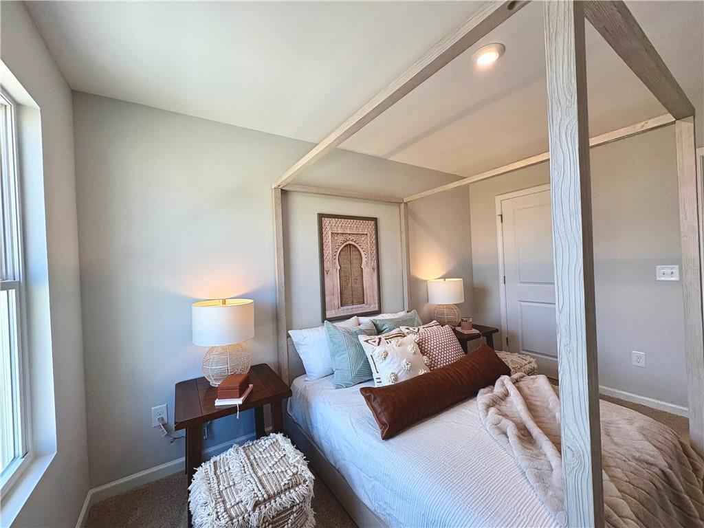 Elegant master bedroom with four-poster king bed, plush pillows, lamps, and arched wall art in Davidson Homes The Monroe A, Emerson, GA
