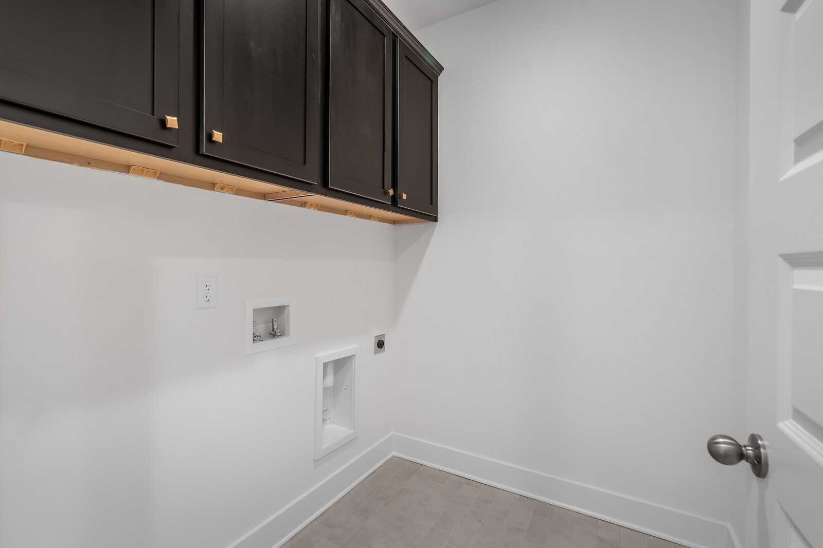 Modern laundry room featuring dark wood upper cabinets, washer/dryer hookups in The Hathaway 4-bedroom home, Murfreesboro, TN