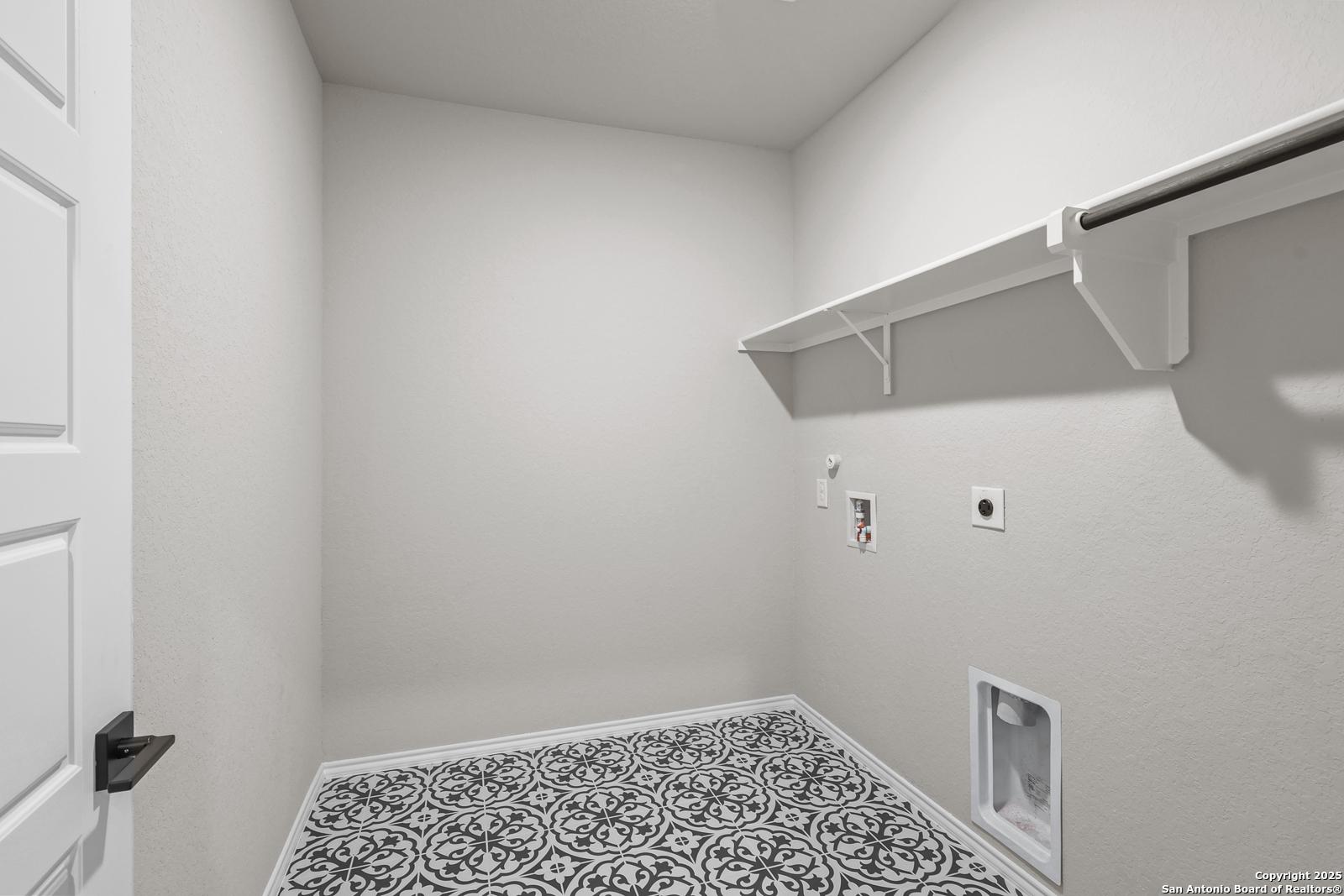 Modern laundry room with open shelves, washer/dryer hookups, and ornate tile floor in Davidson Homes The Murray J, San Antonio