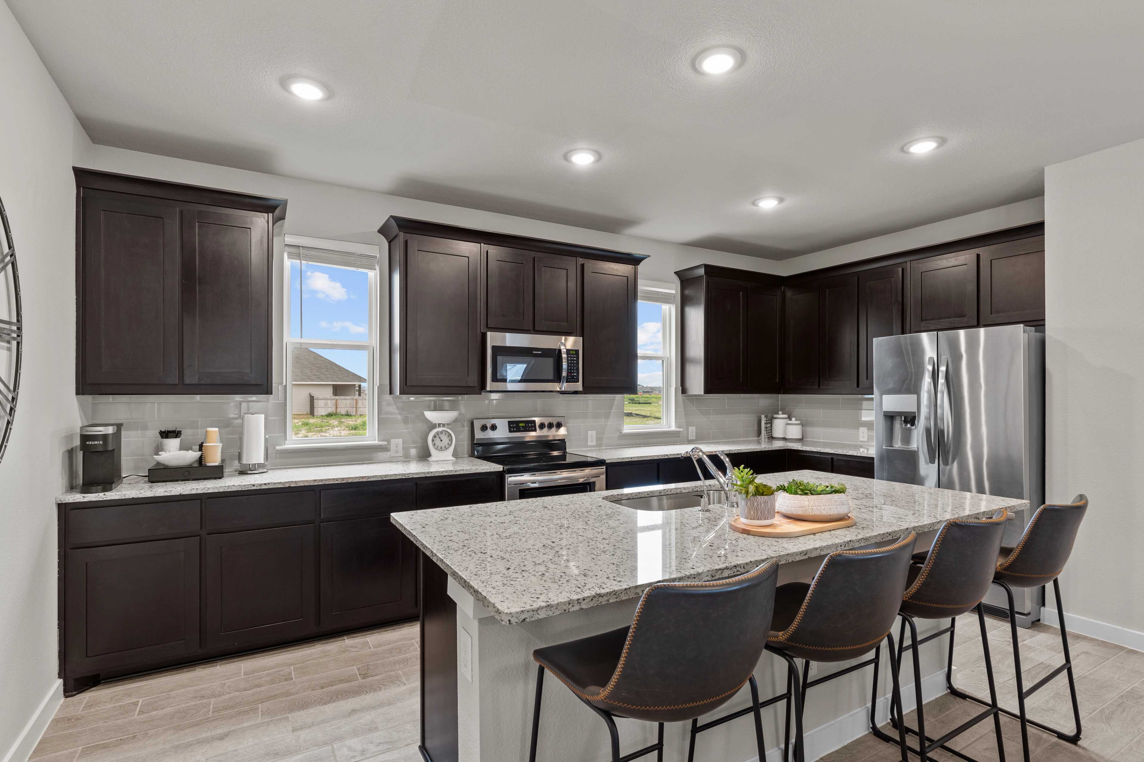 Spacious modern kitchen with dark wood cabinets, quartz island, stainless appliances at Hannah Heights in Seguin, Texas