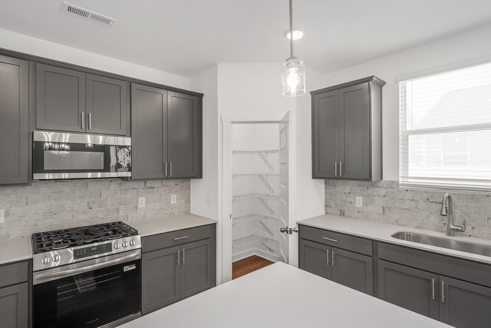 Modern gray kitchen with shaker cabinets, stainless steel appliances, subway tile backsplash in Davidson Homes The Gordon C, White House, TN